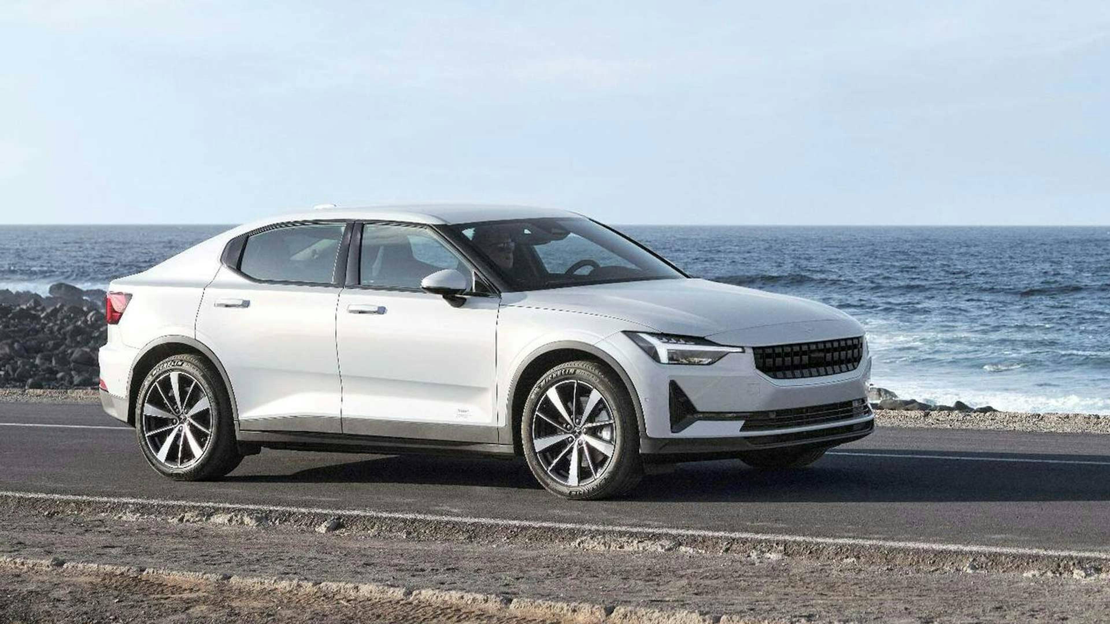 Ein heller Polestar 2 Long Range fährt eine Küstenstraße entlang.