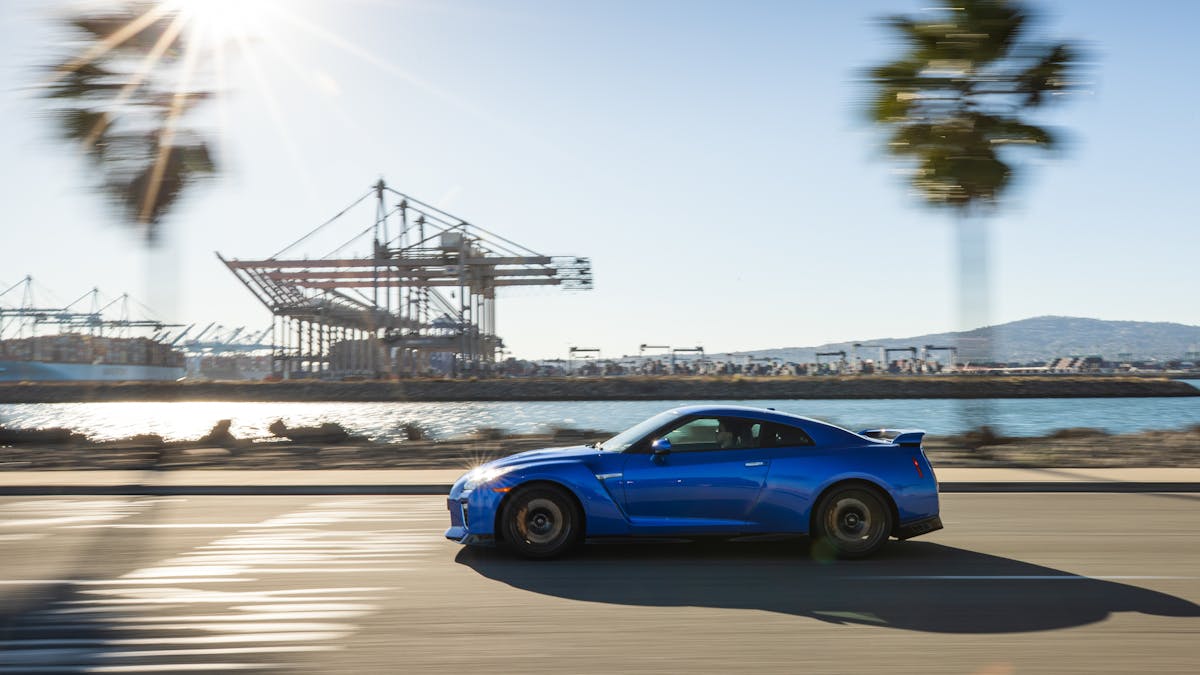 Ein blauer Nissan GT-R fährt an einem Hafen vorbei