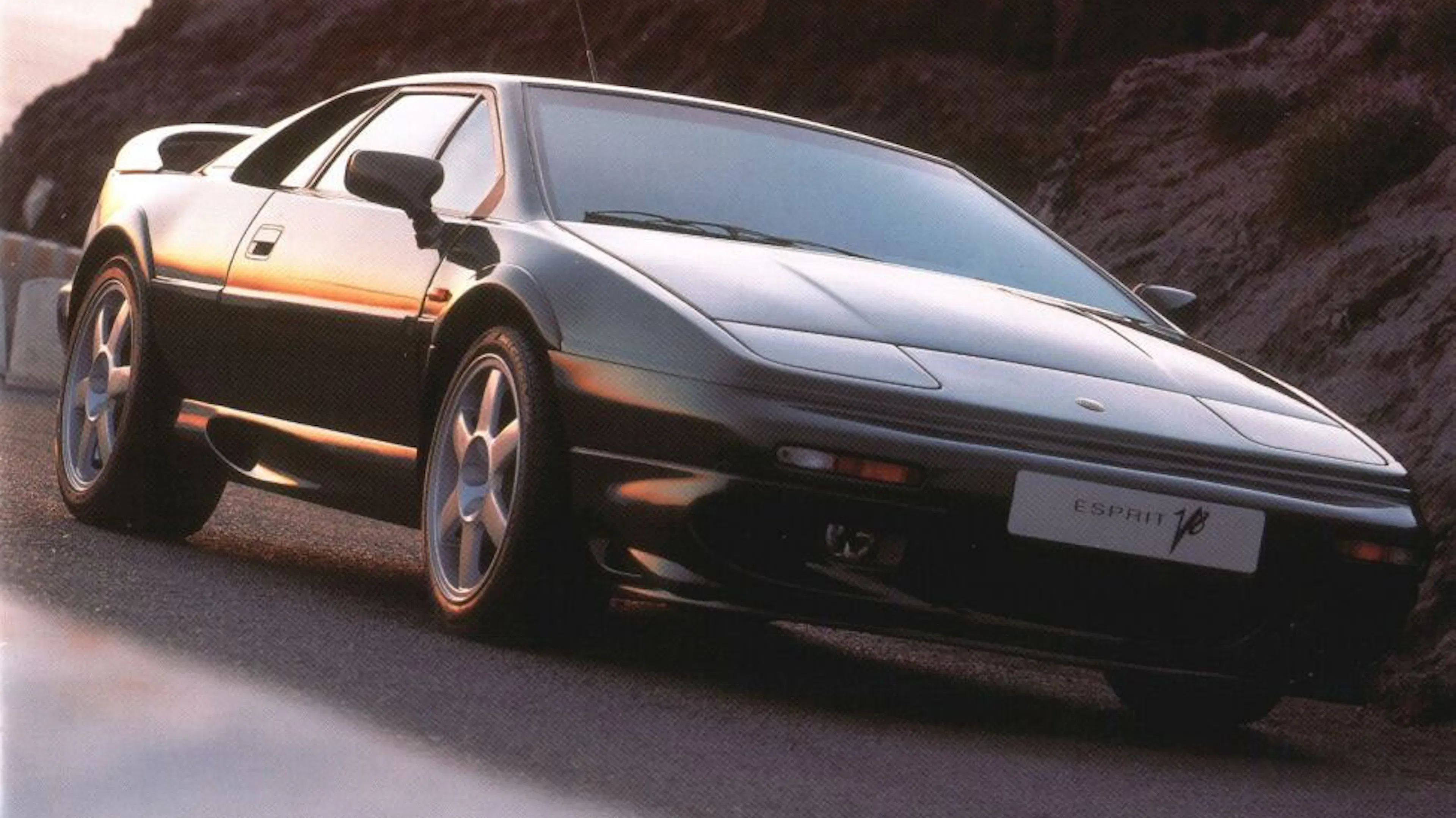 Ein schwarzer Lotus Esprit V8 fährt auf einer Landstraße.