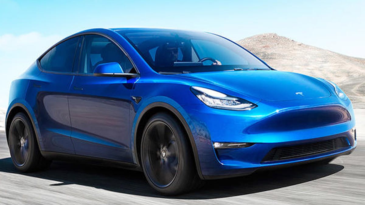 Ein blaues Tesla Model Y fährt eine Landstraße entlang.