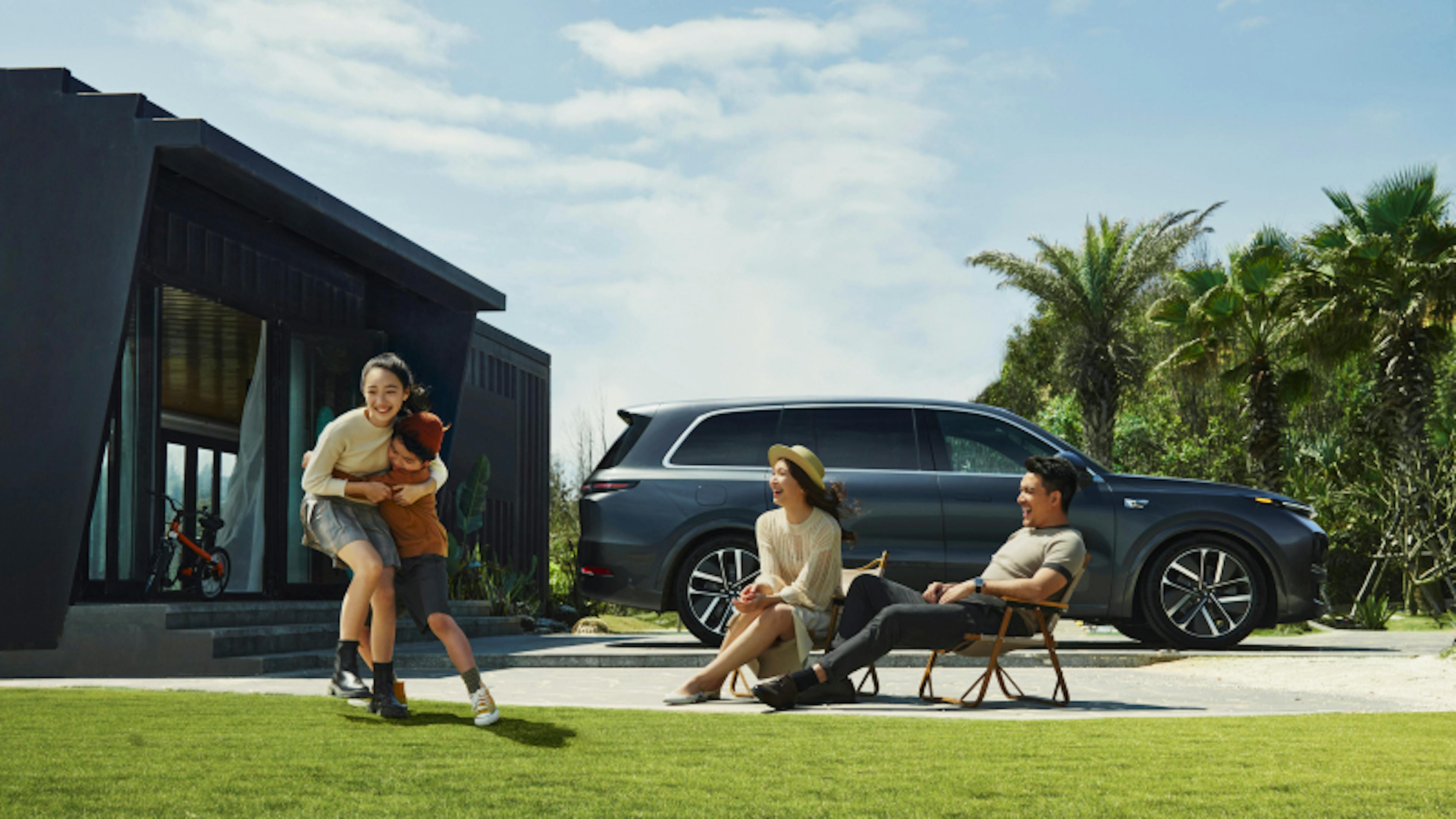 A family with two children playing in front of a Li L9.