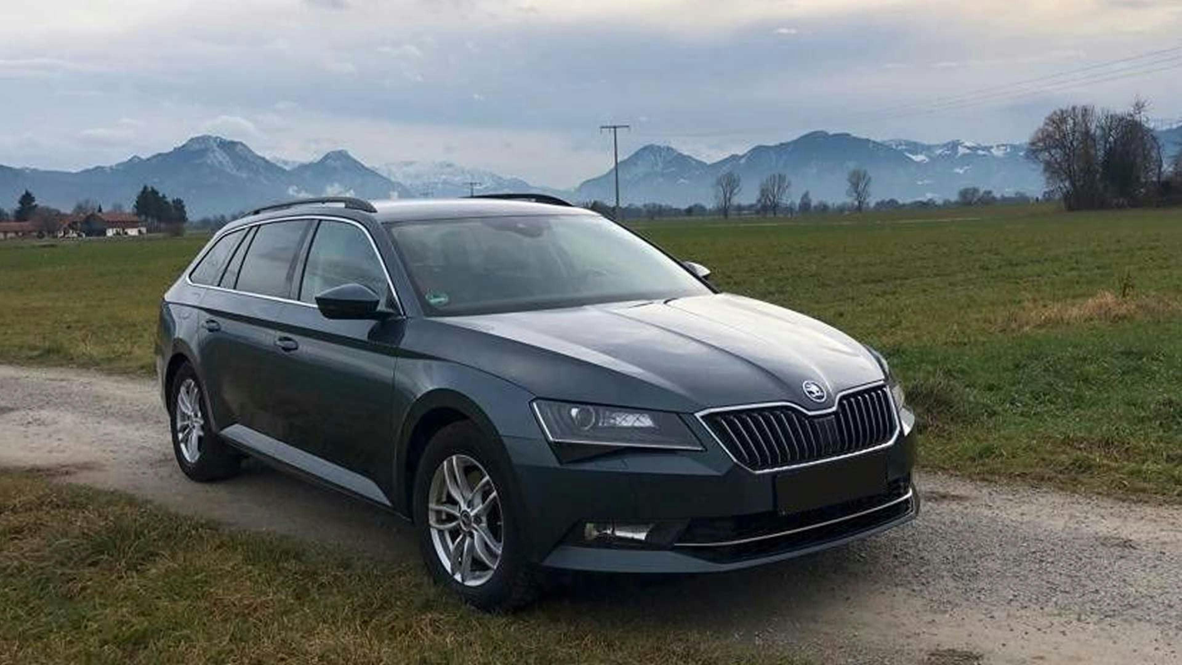 Ein schwarzer Škoda Superb Combi steht auf einem Feldweg.