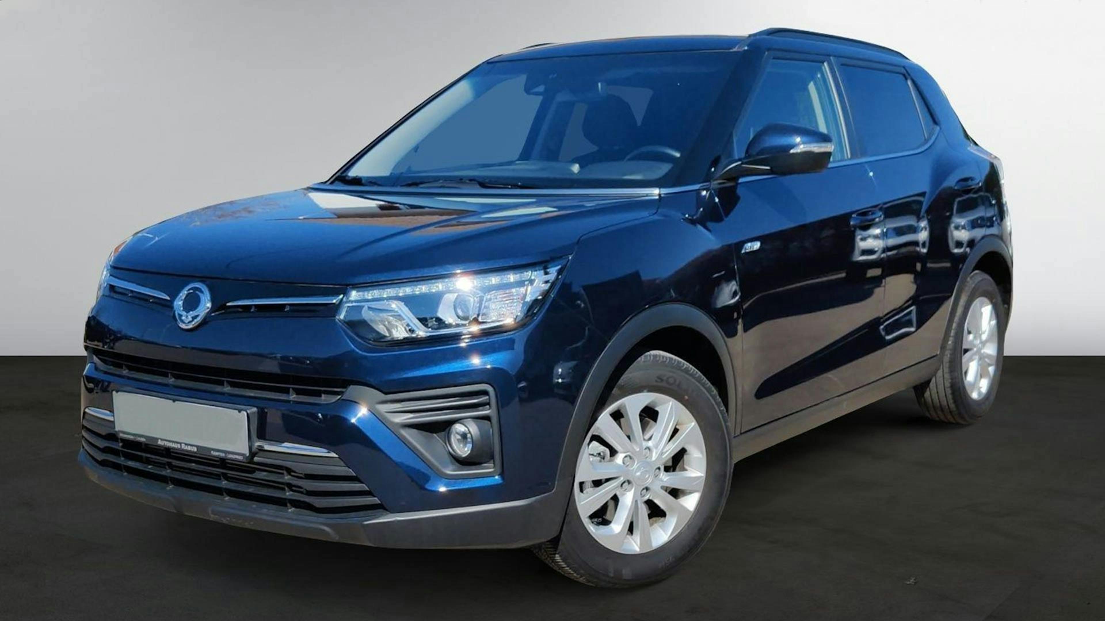 Ein dunkelblauer SsangYong Tivoli steht vor einer weißen Wand.