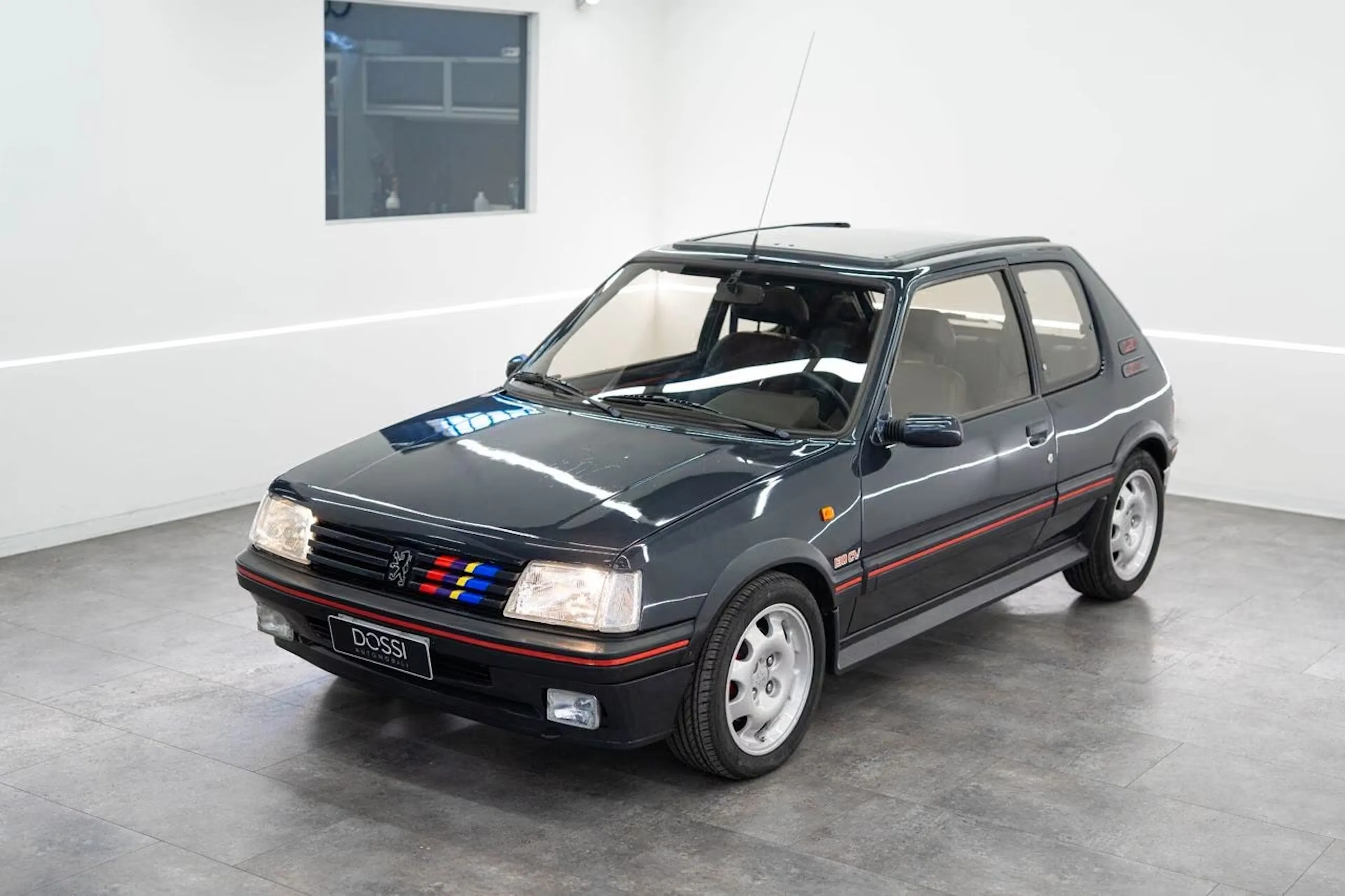 Schwarzer Peugeot 205 steht in einem weißen Raum.
