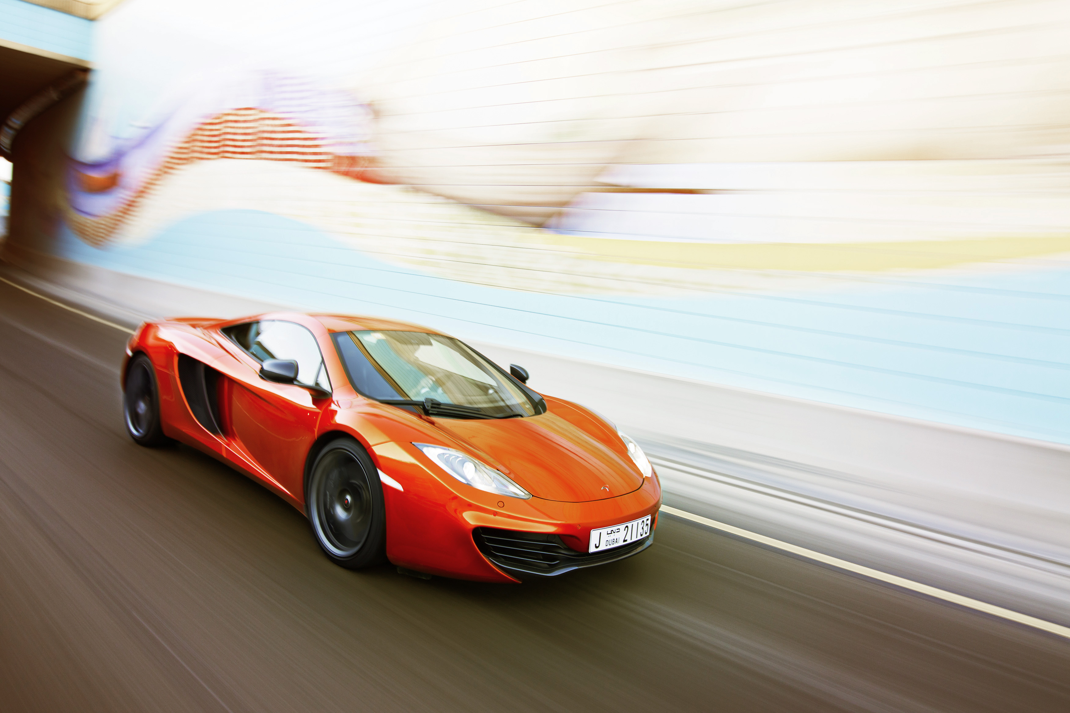 Ein orangefarbener McLaren MP4-12C fährt auf einer Straße.