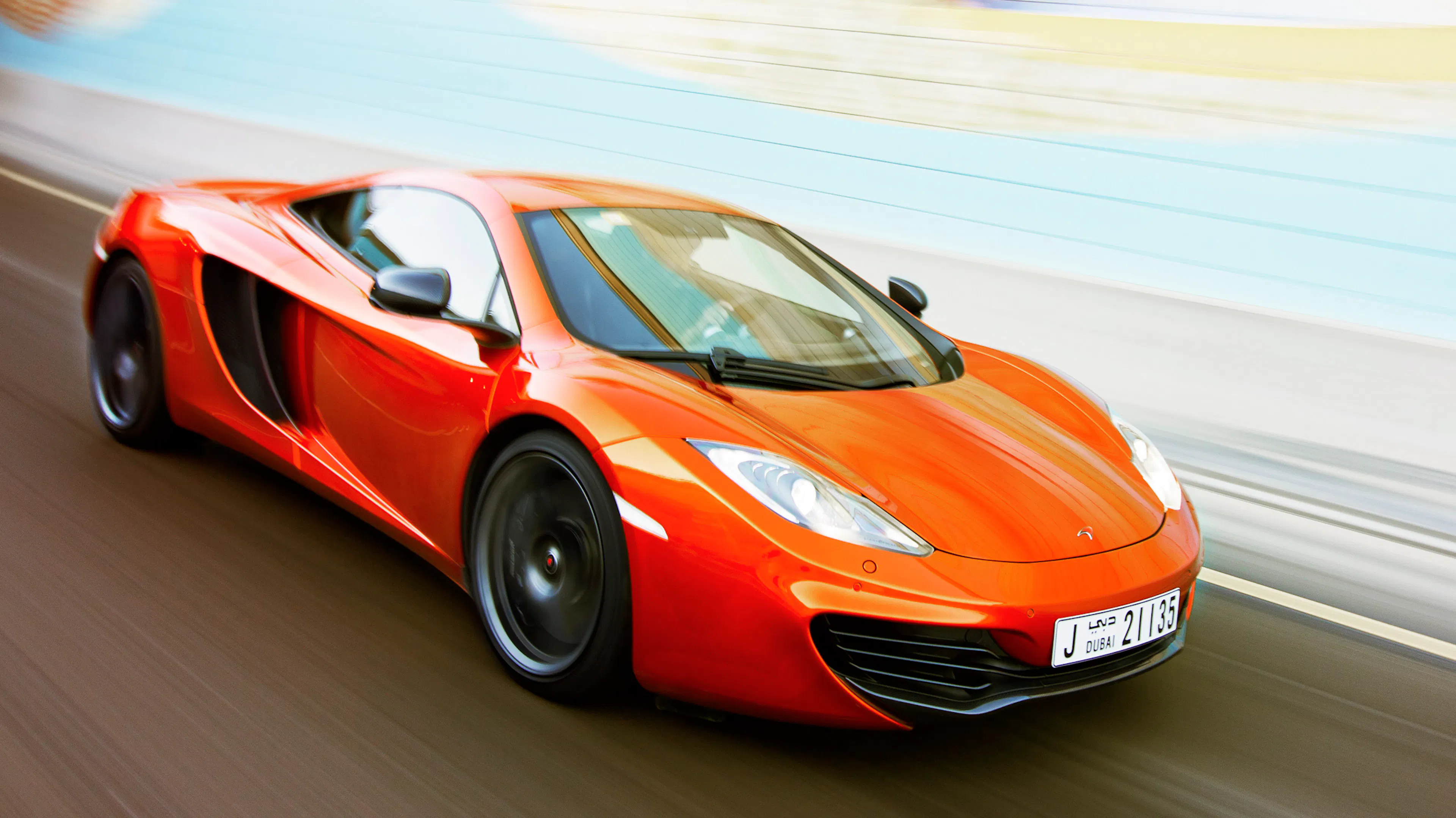 Ein orangefarbener McLaren MP4-12C fährt auf einer Straße.