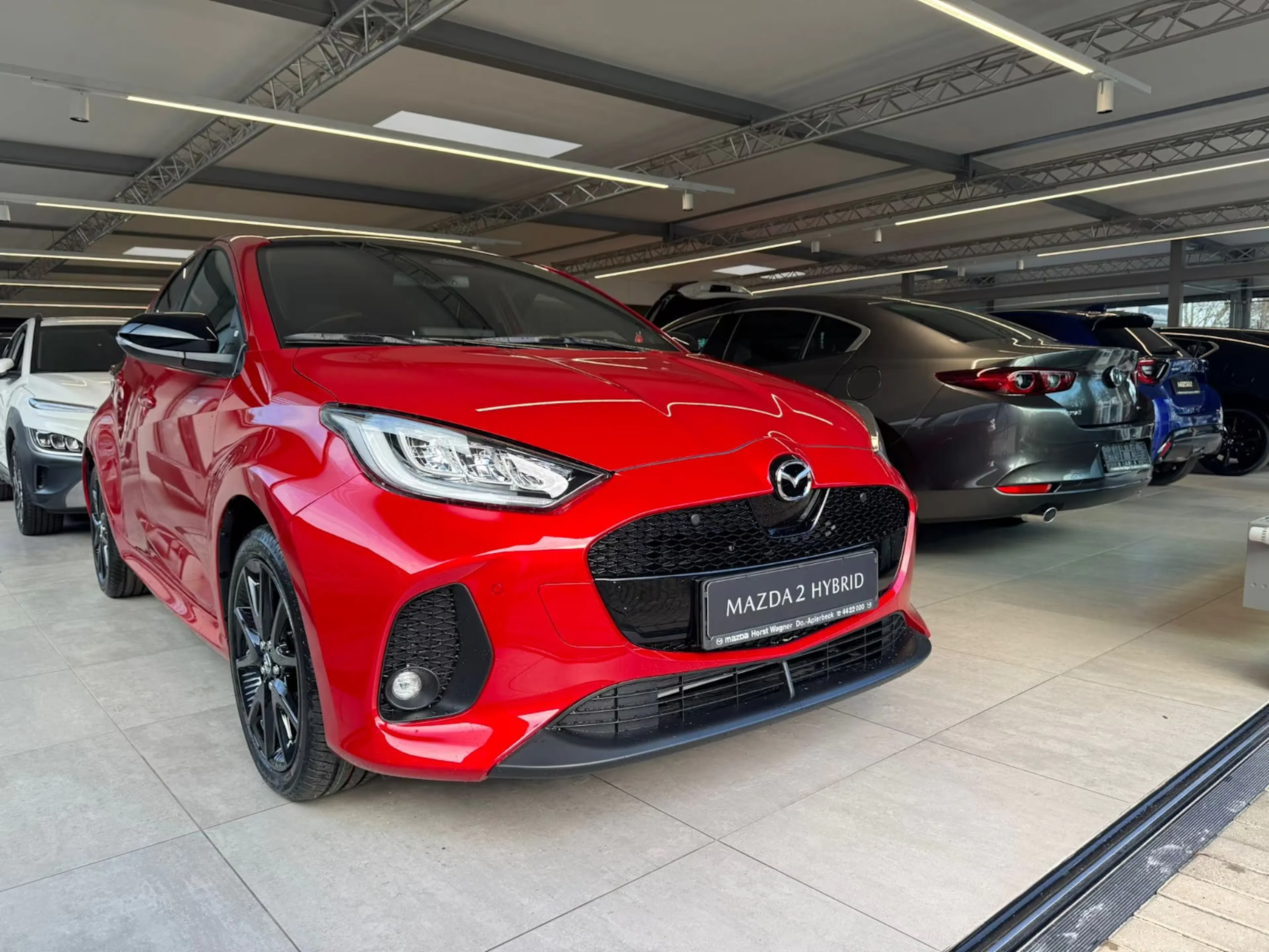Ein roter Mazda2 steht in einer Verkaufshalle.