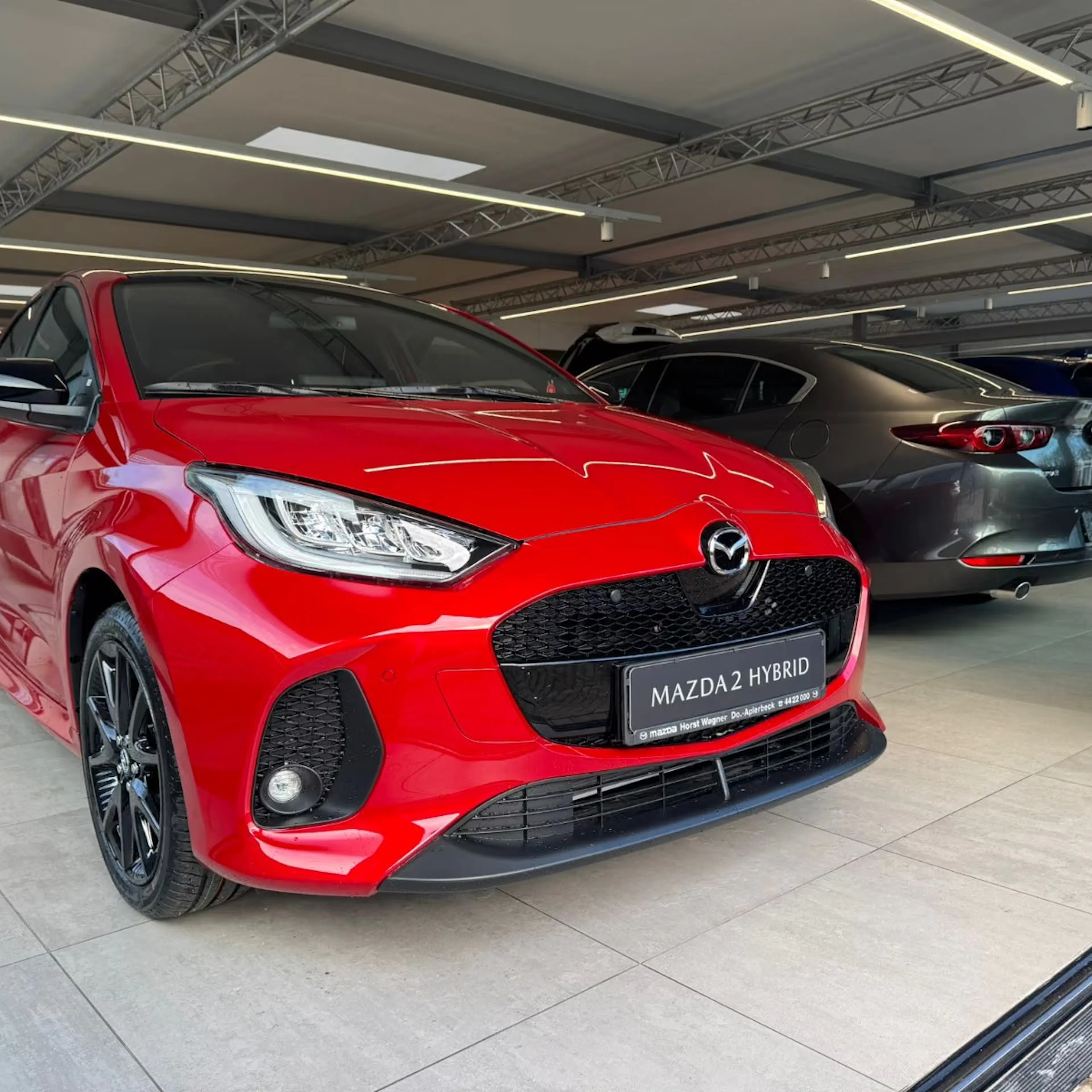 Ein roter Mazda2 steht in einer Verkaufshalle.