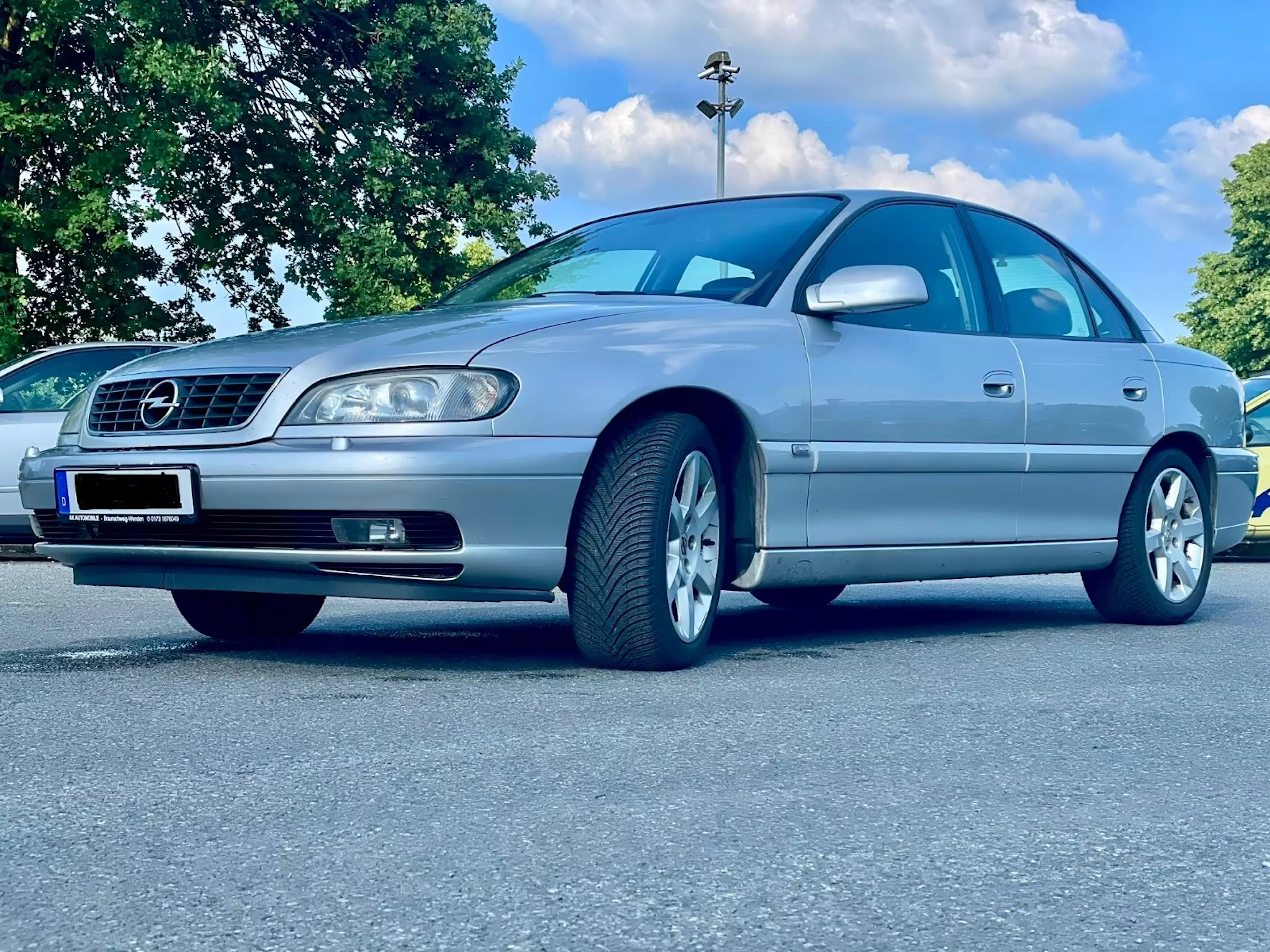 Ein silberner Opel Omega steht auf einem Platz.