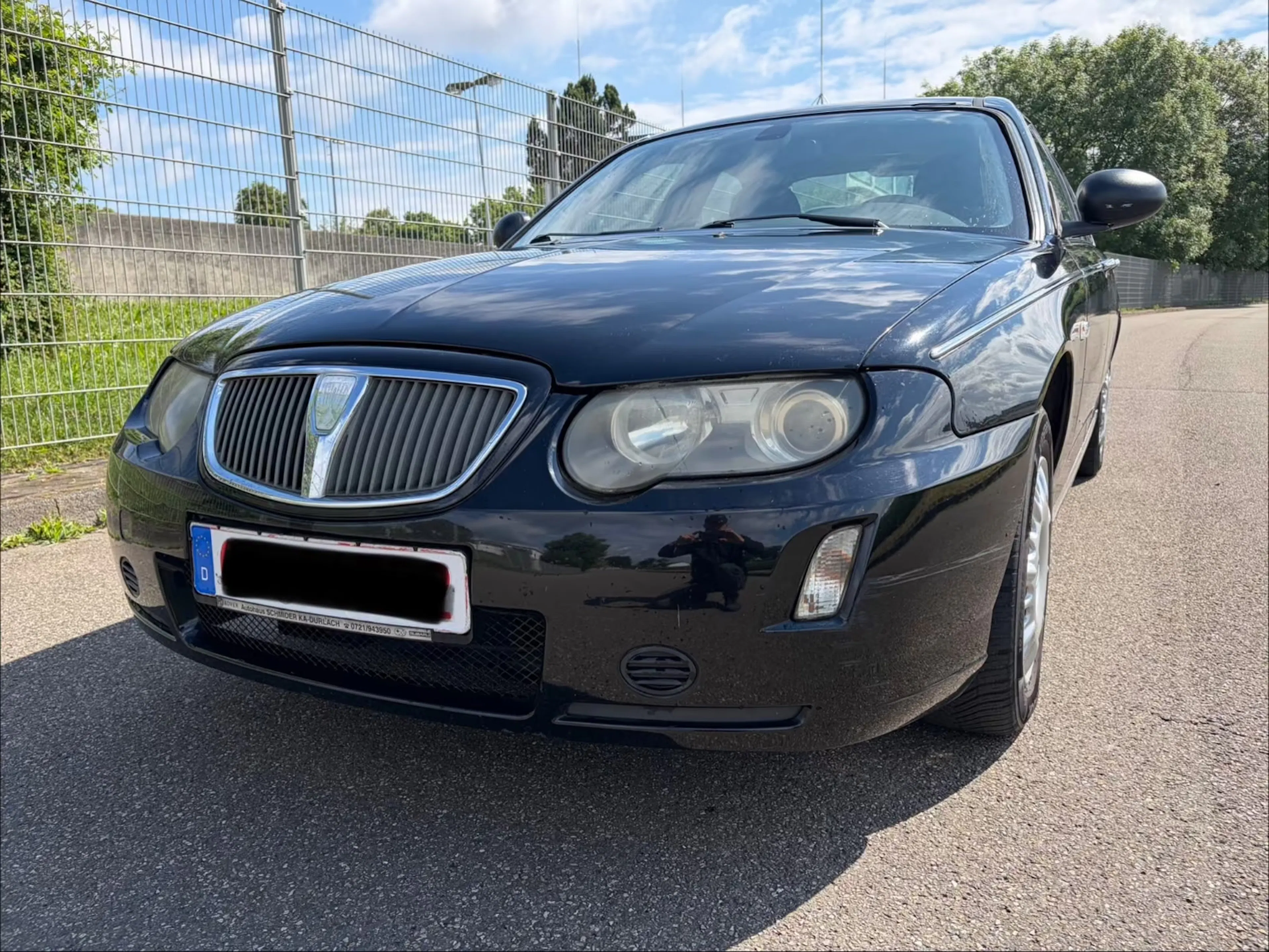 Schwarzer Rover 75 steht vor einem Zaun