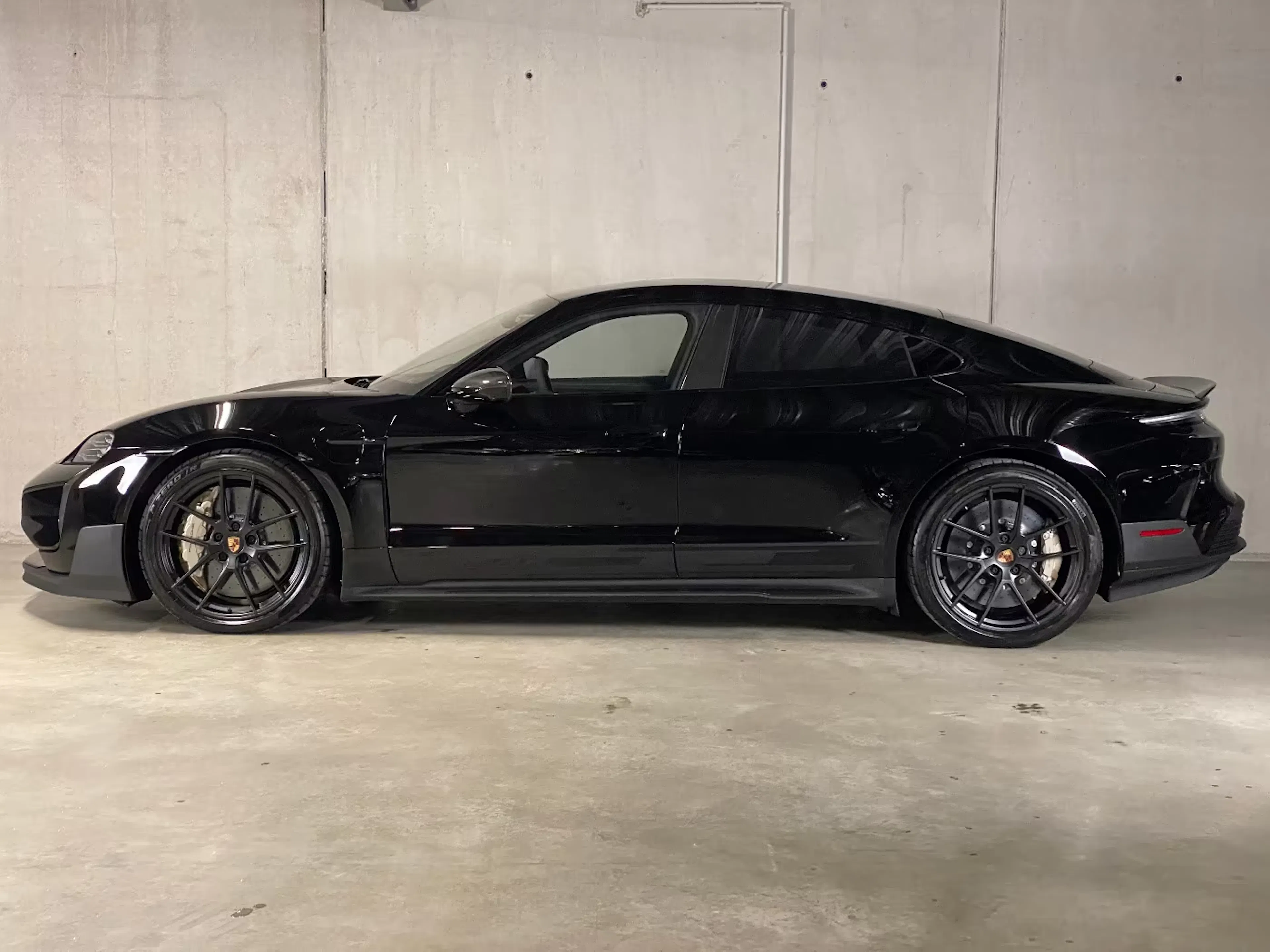 Ein Porsche Taycan Turbo GT steht auf einer betonierten Fläche.