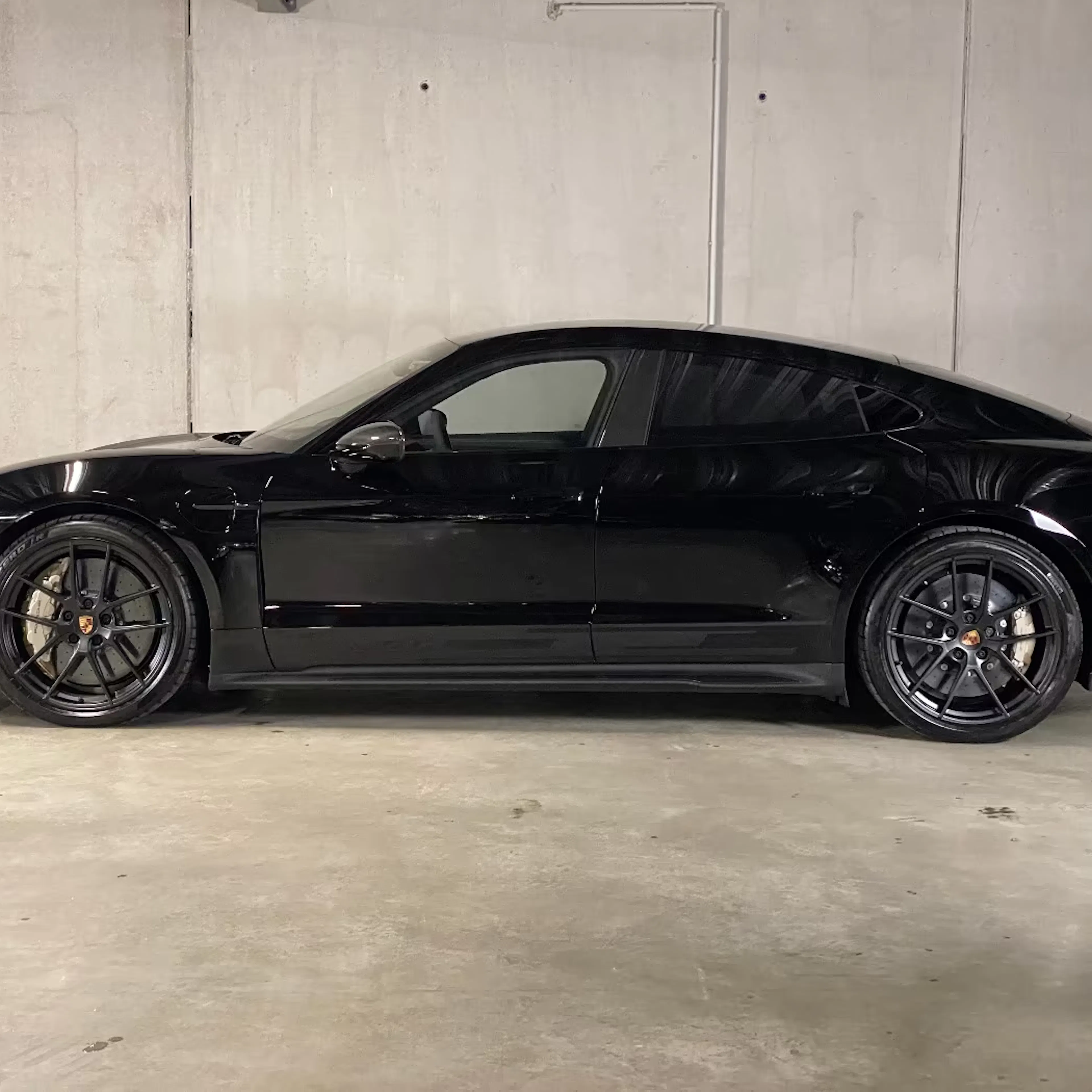 Ein Porsche Taycan Turbo GT steht auf einer betonierten Fläche.
