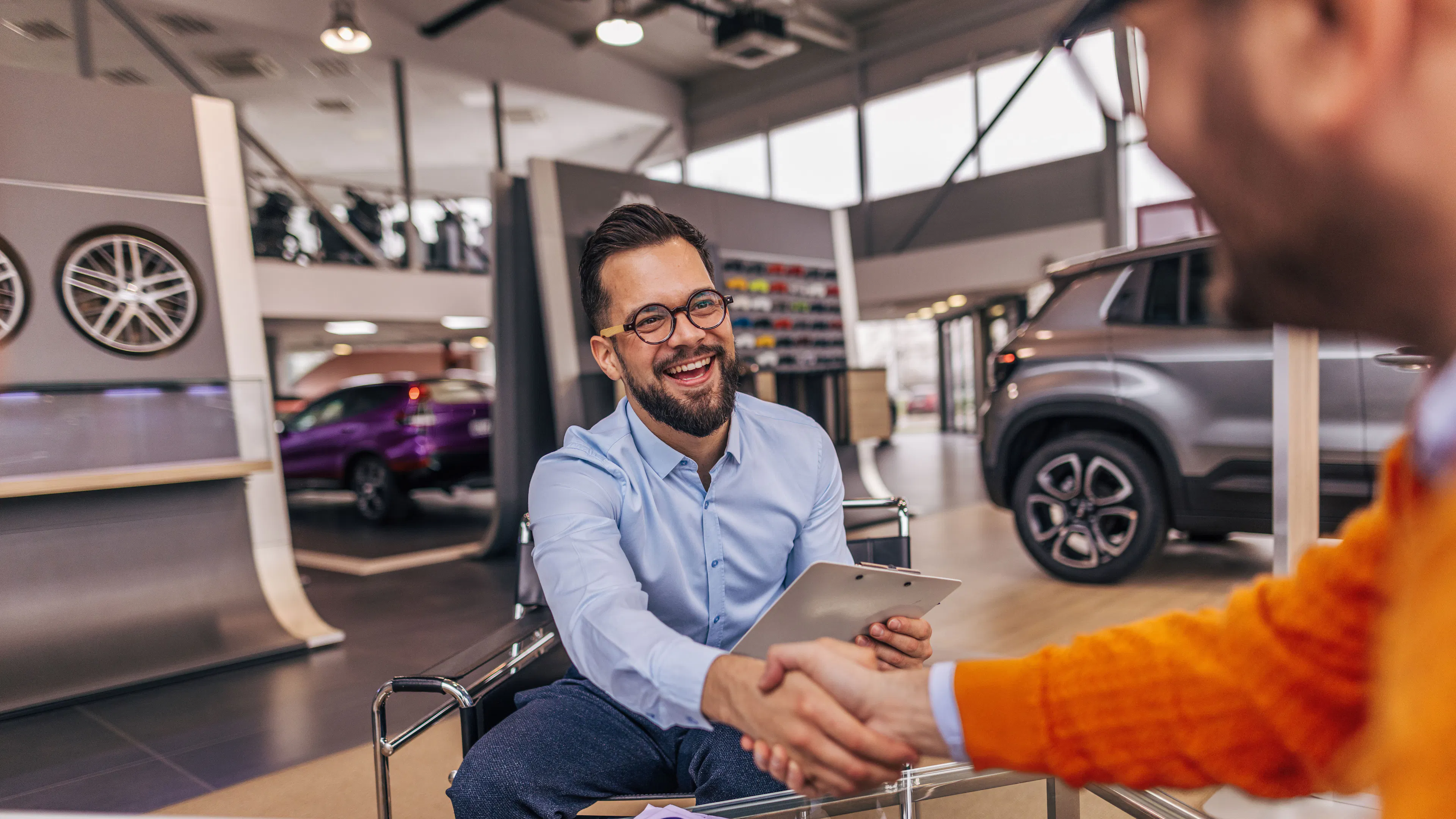 Ein Mann schüttelt einem anderen Mann in einem Autohaus die Hand.