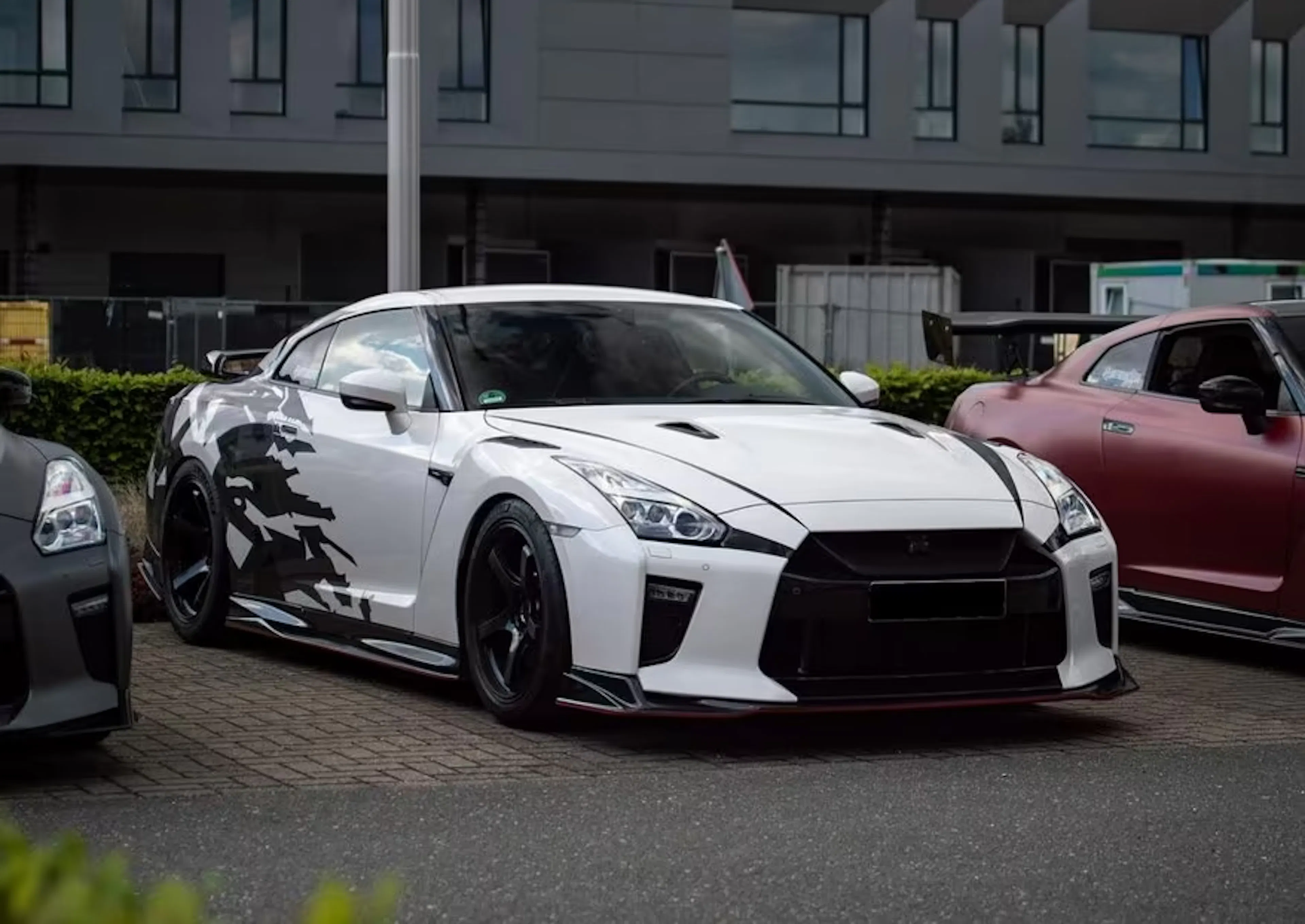 Ein weißer Nissan GT R steht auf einem Parkplatz.