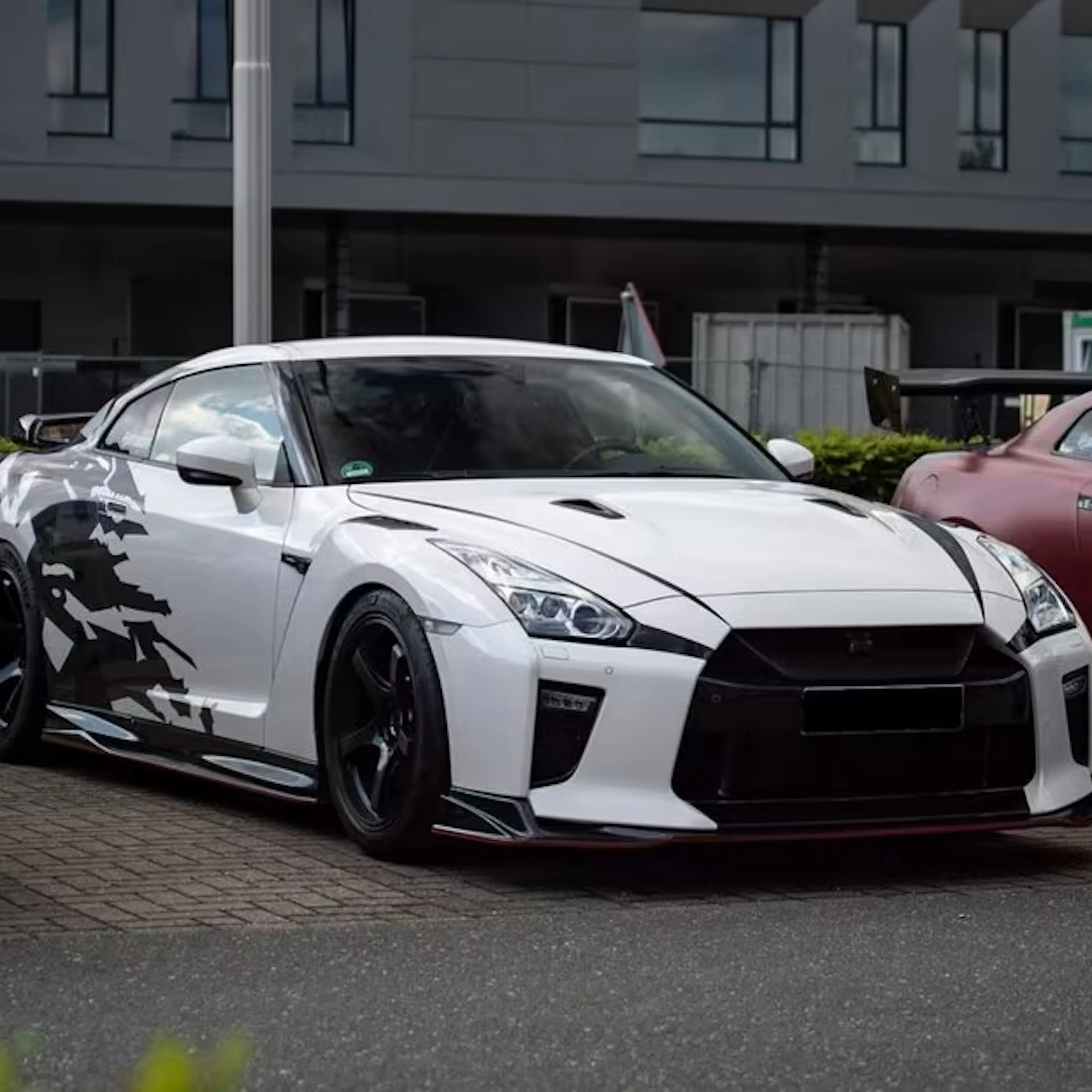 Ein weißer Nissan GT R steht auf einem Parkplatz.