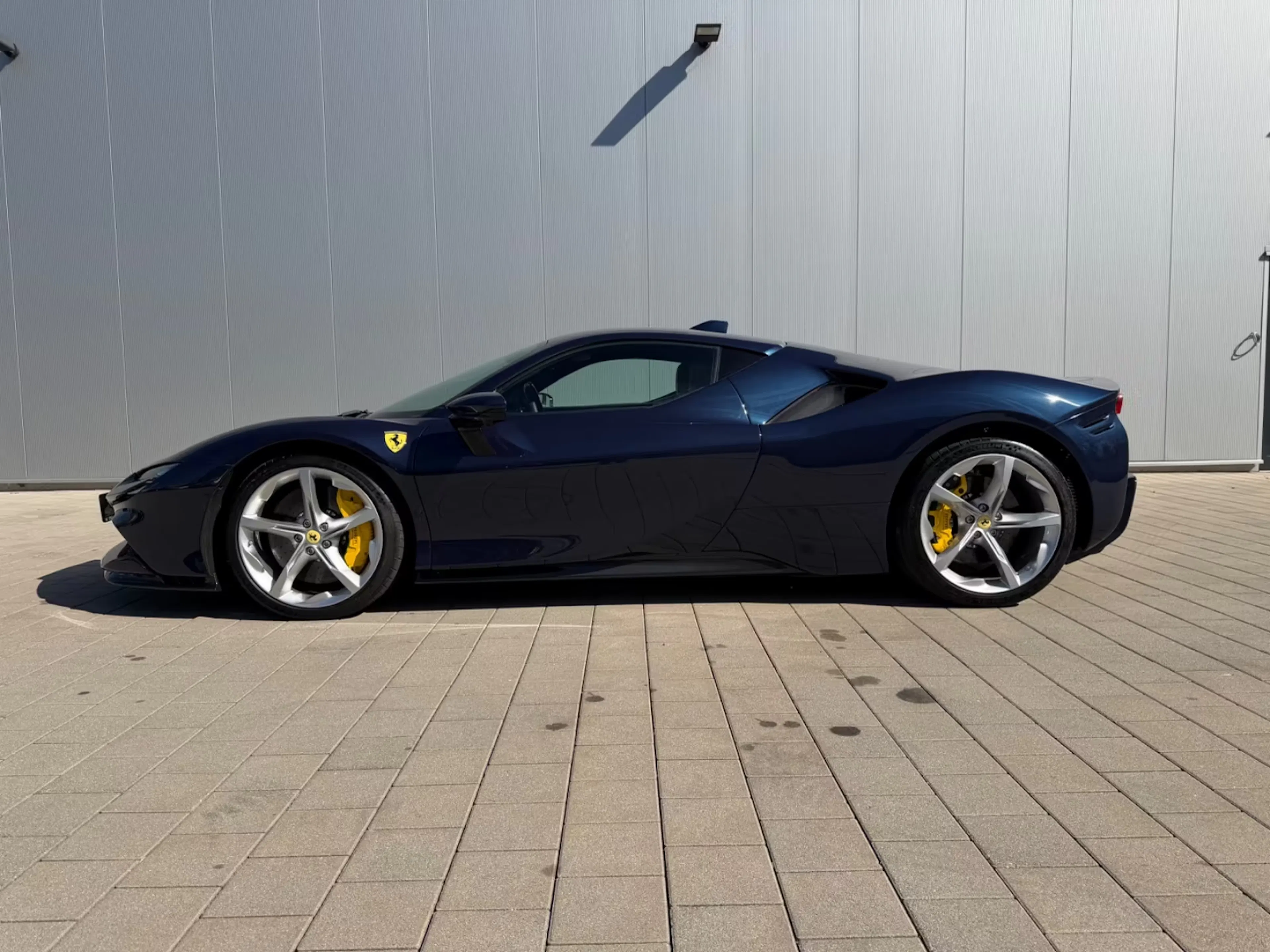 Dunkelblauer Ferrari Stradale vor grauer Wand