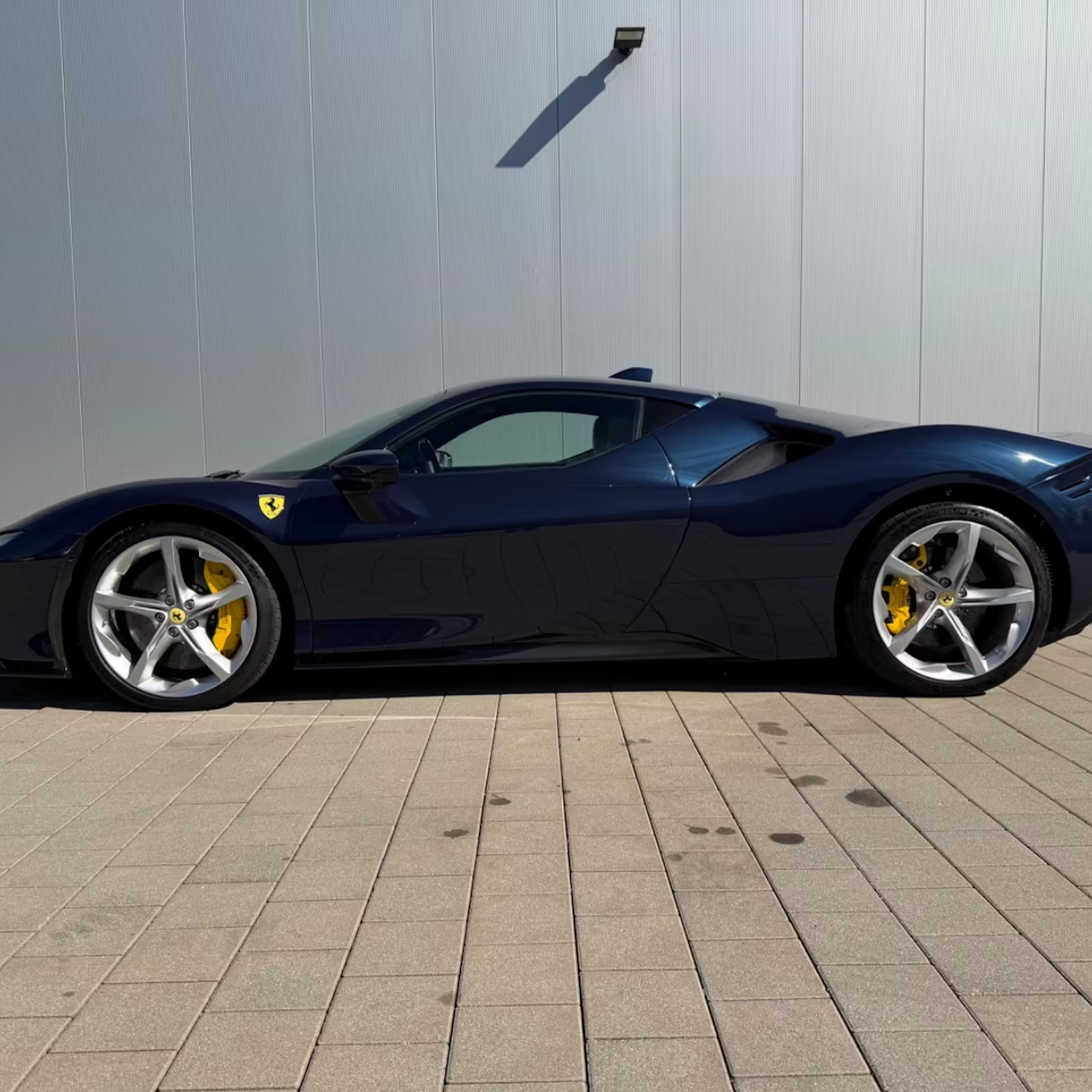Dunkelblauer Ferrari Stradale vor grauer Wand