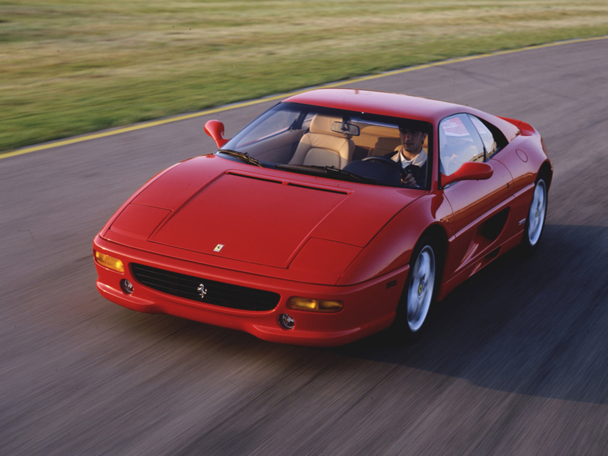 Roter Ferrari F355 Berlinetta in der Dreiviertel-Frontansicht auf einer Rennstrecke, dynamische Aufnahme.