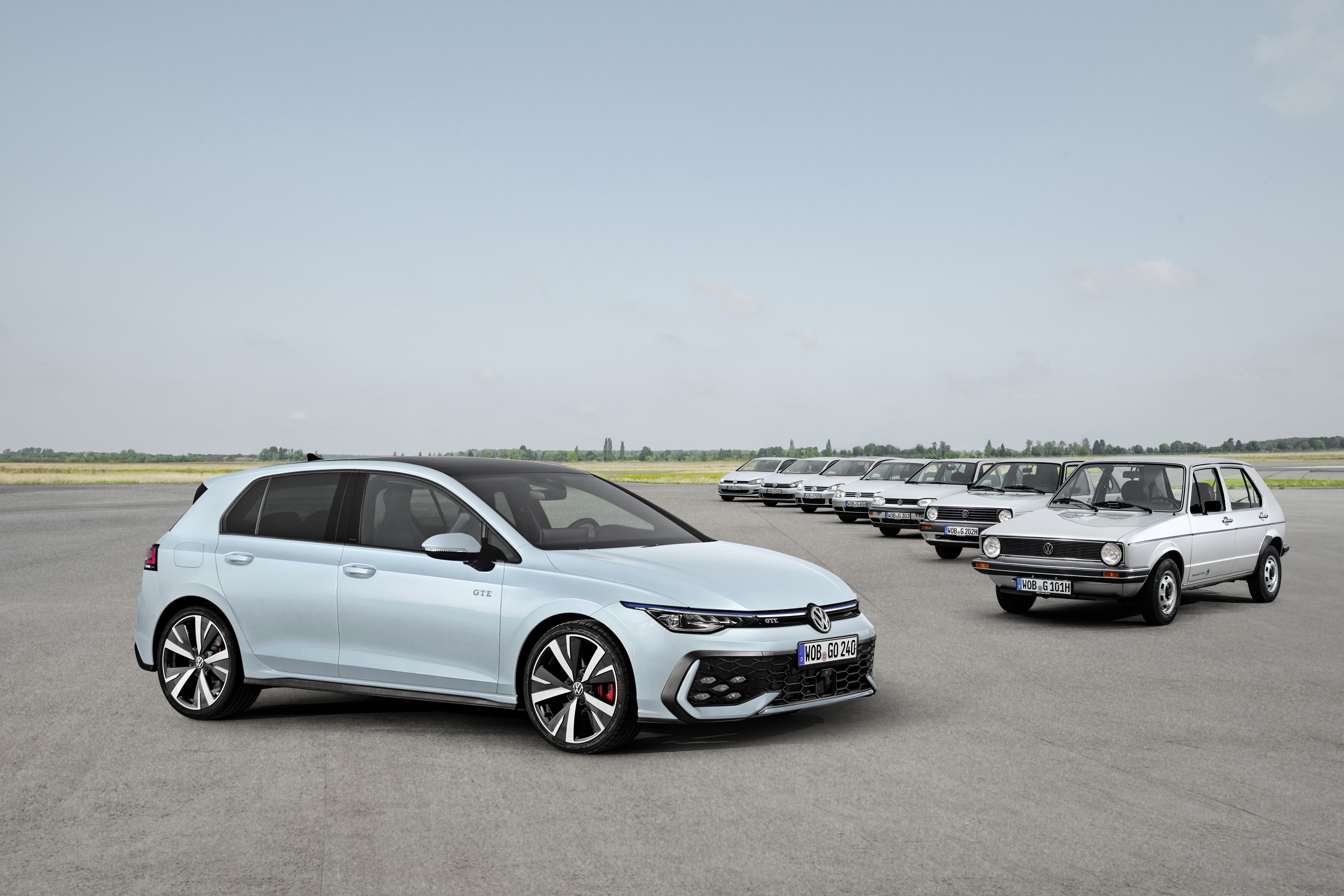 Reihe von acht Volkswagen-Golf-Generationen auf einem Flugplatz, von historisch bis aktuell.