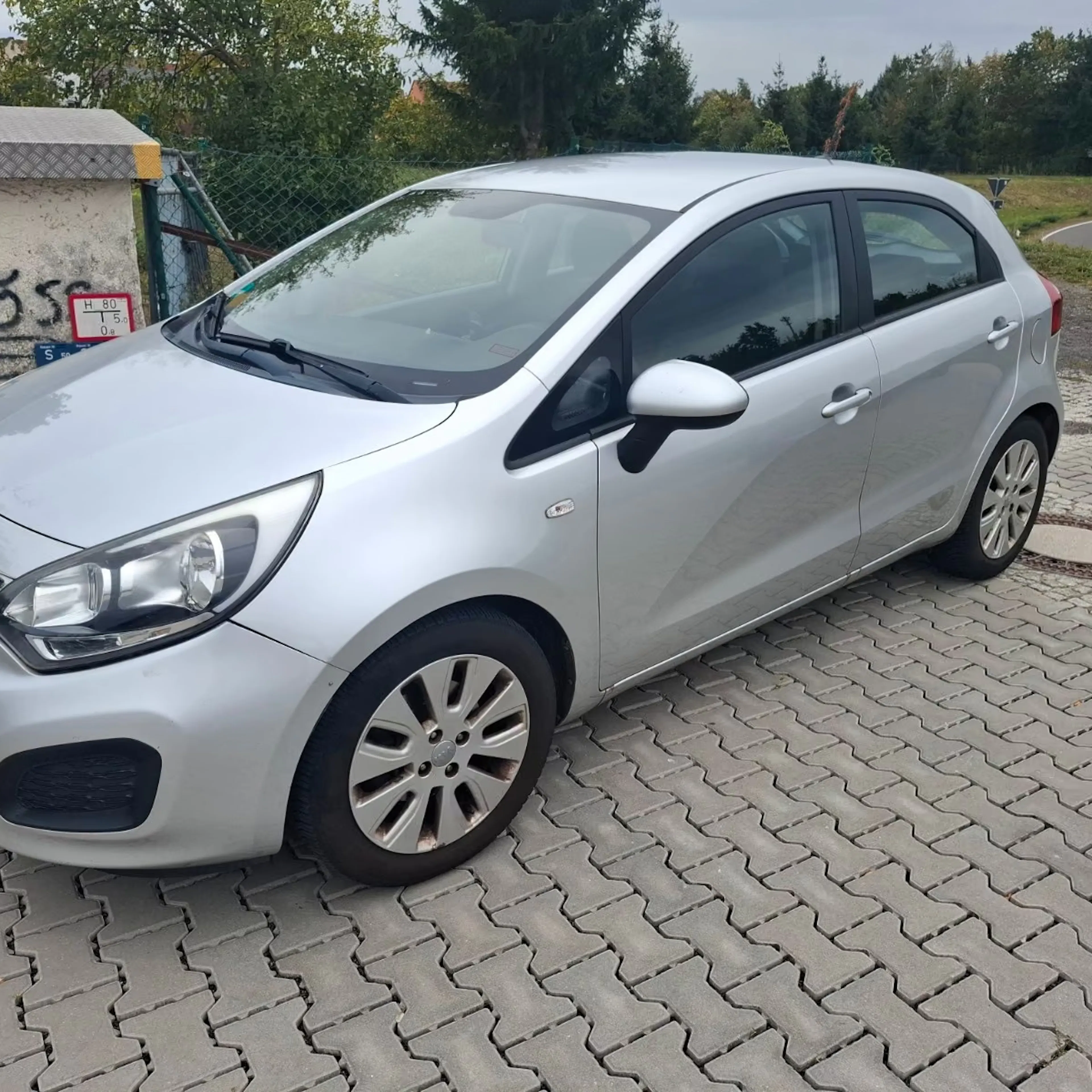 Silberner Kia Rio steht auf gepflastertem Platz