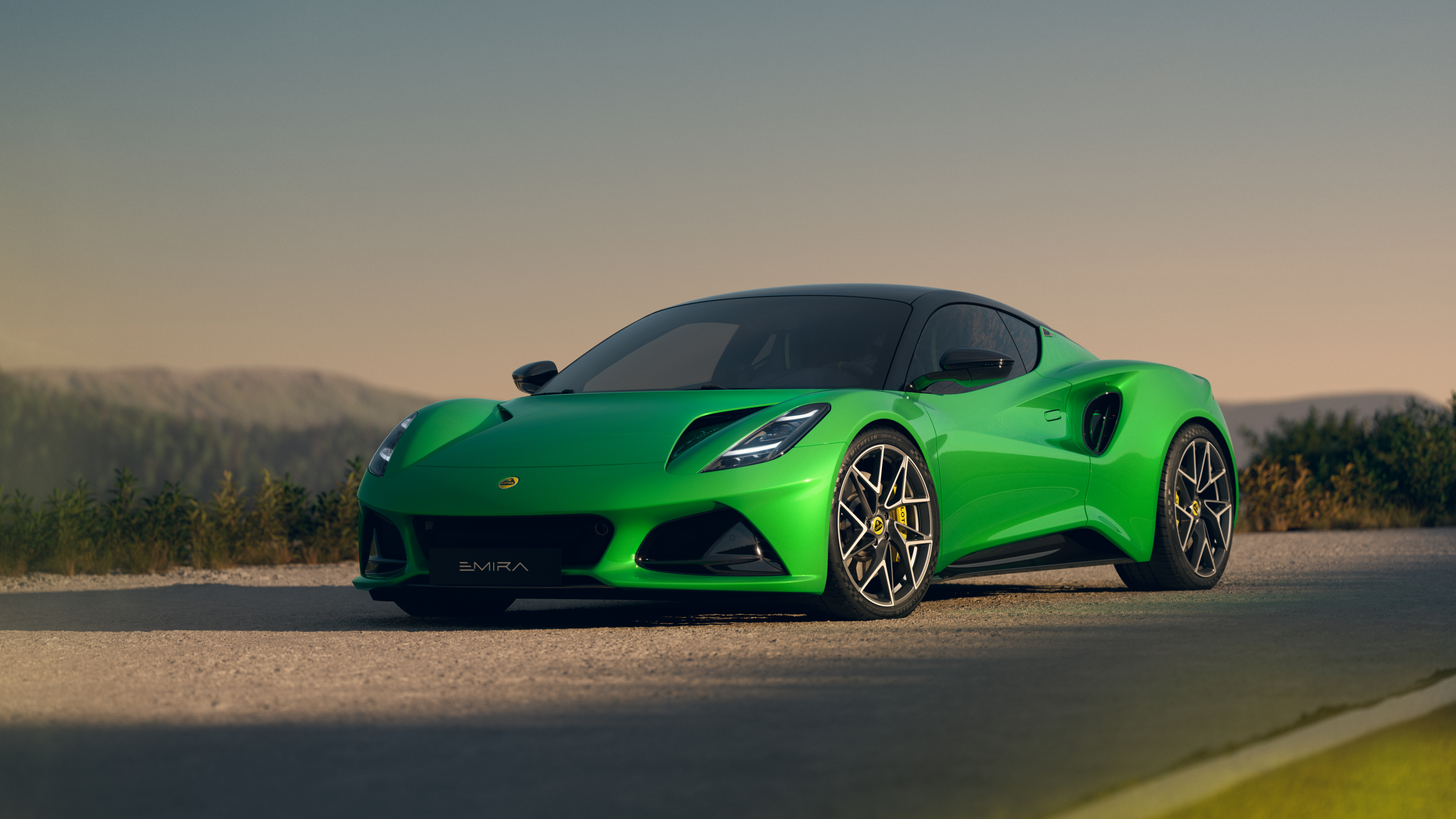 Lotus Emira V6 SE, statische Aufnahme von der Seite und Front auf einer Straße.