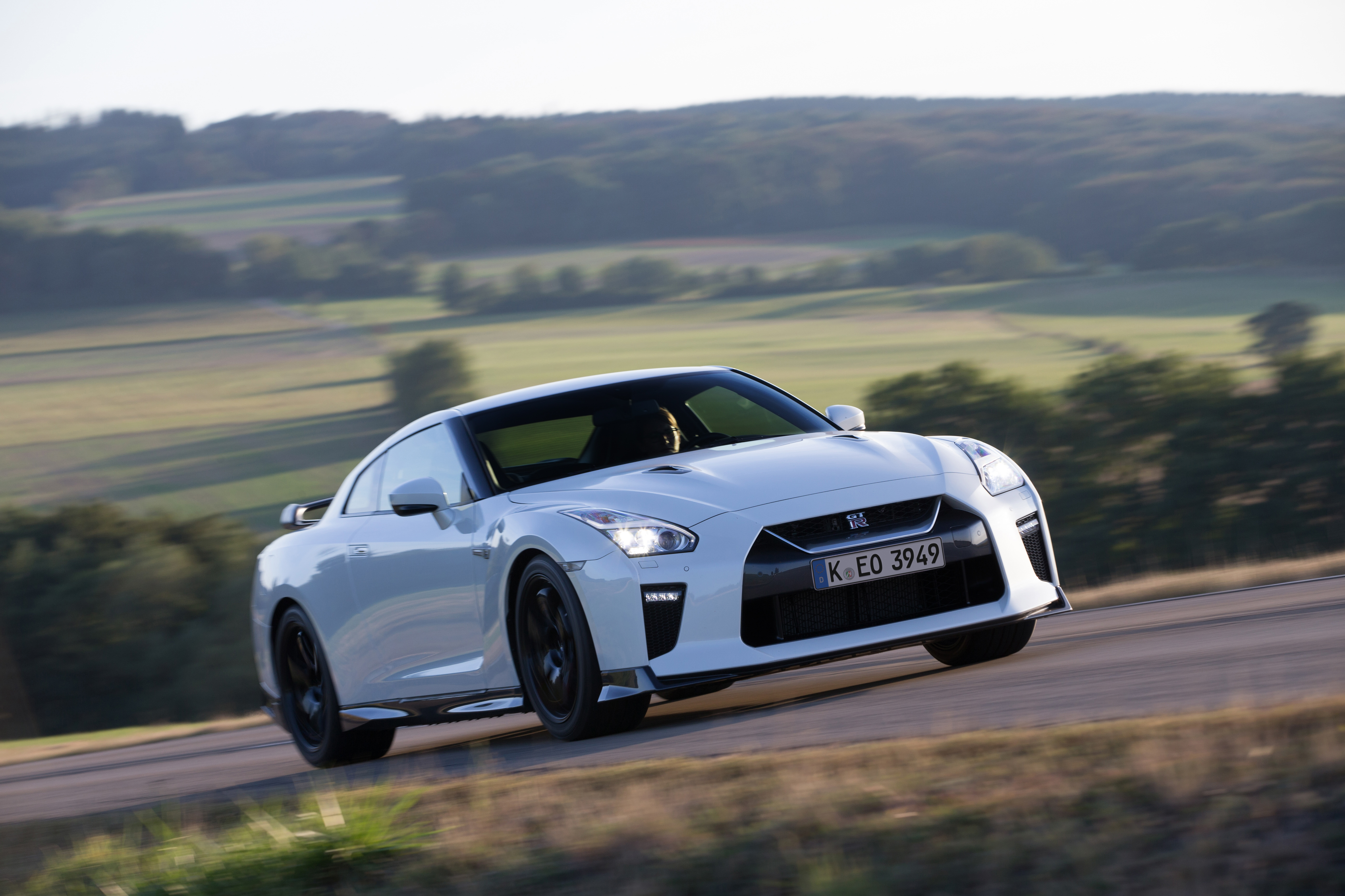 Ein weißer Nissan GT R fährt auf einer Landstraße.