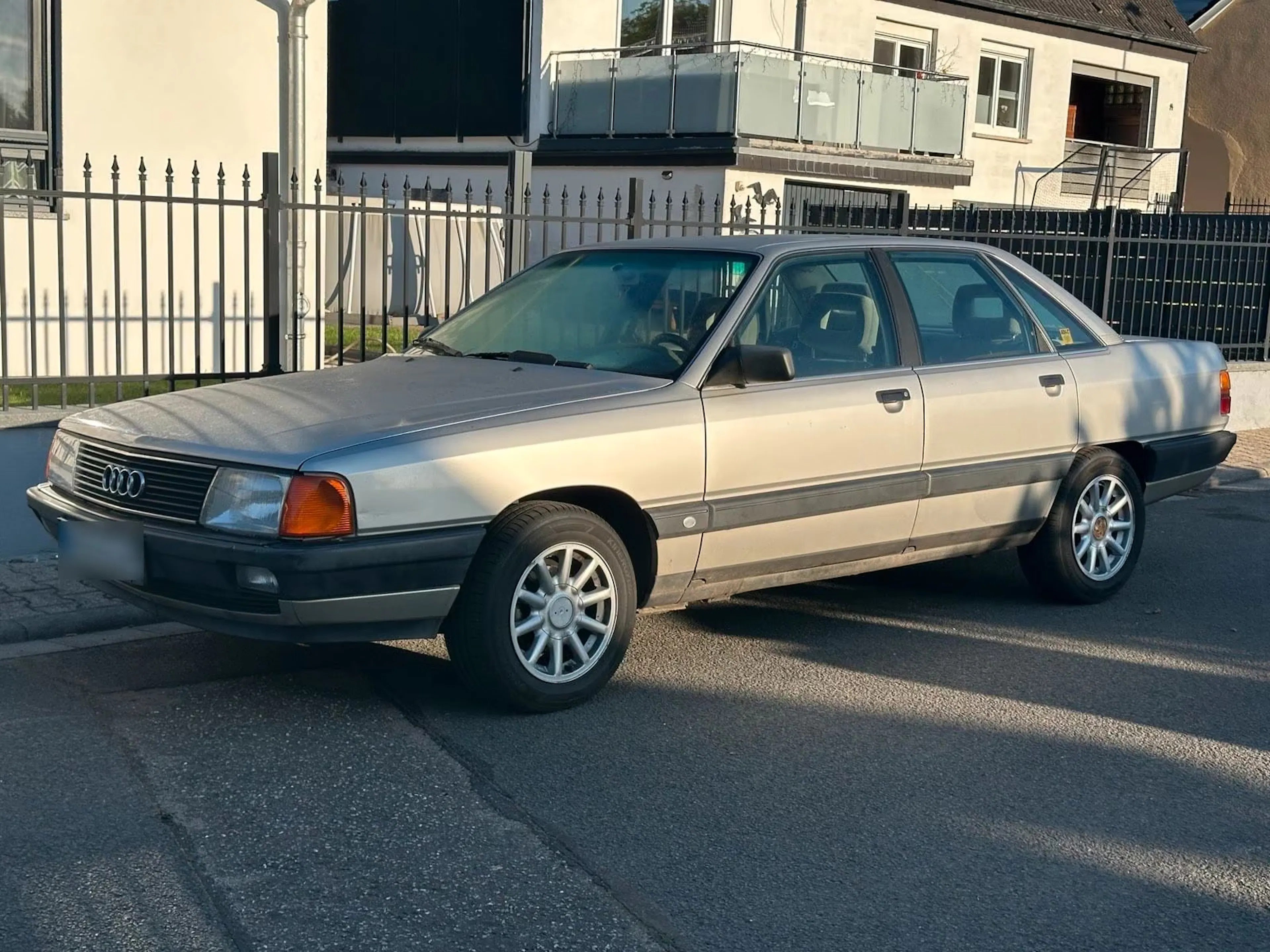 Silberner Audi 100 C3 vor Reihenhaus