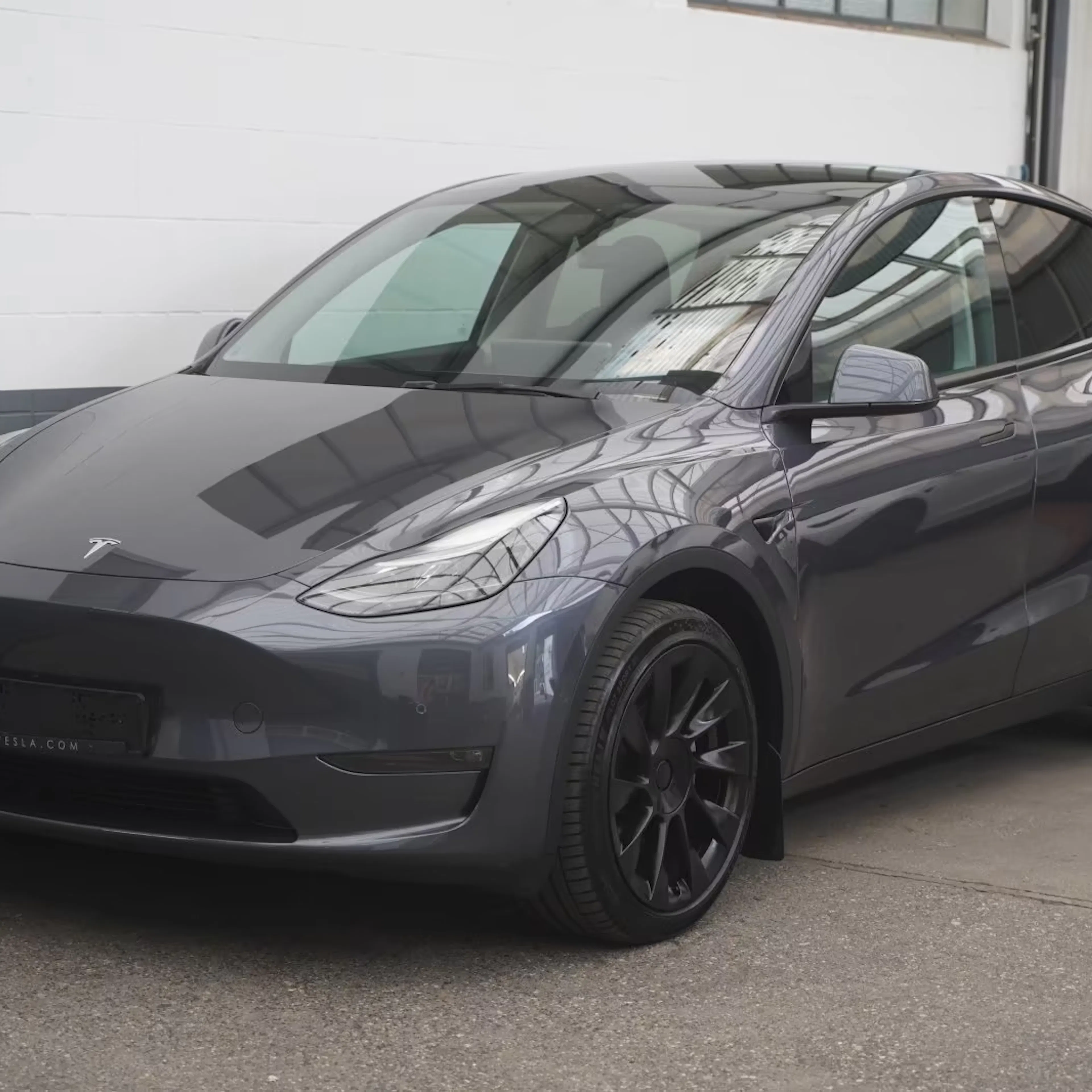 Ein dunkelgrauer Tesla steht auf einer Verkaufsfläche.