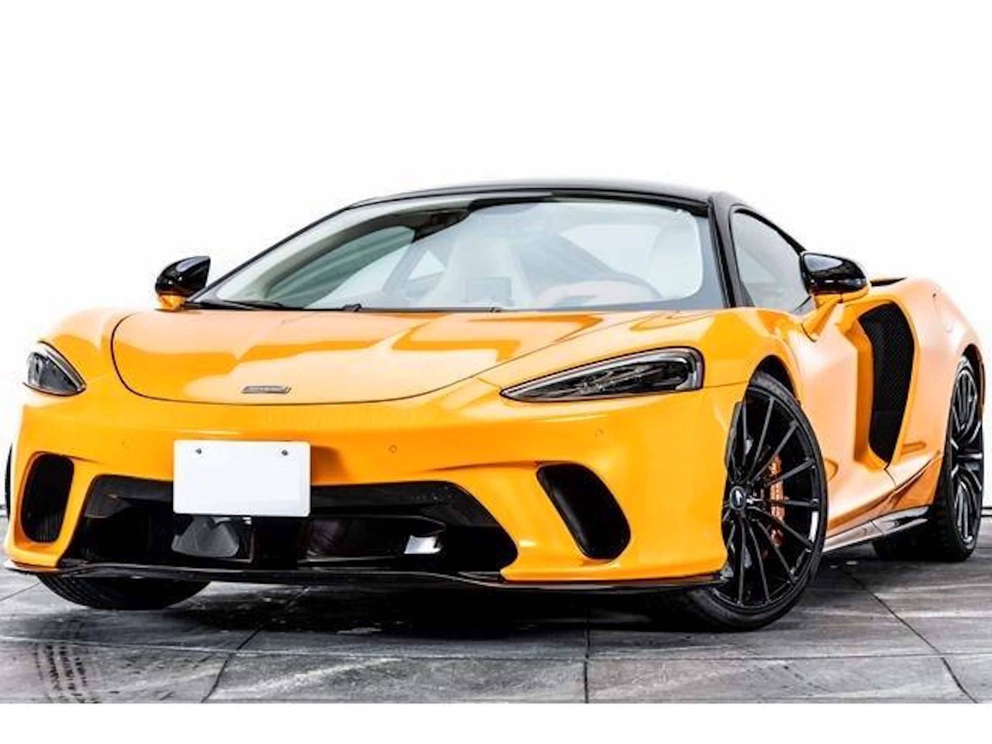 Gelber McLaren GT vor weißer Wand