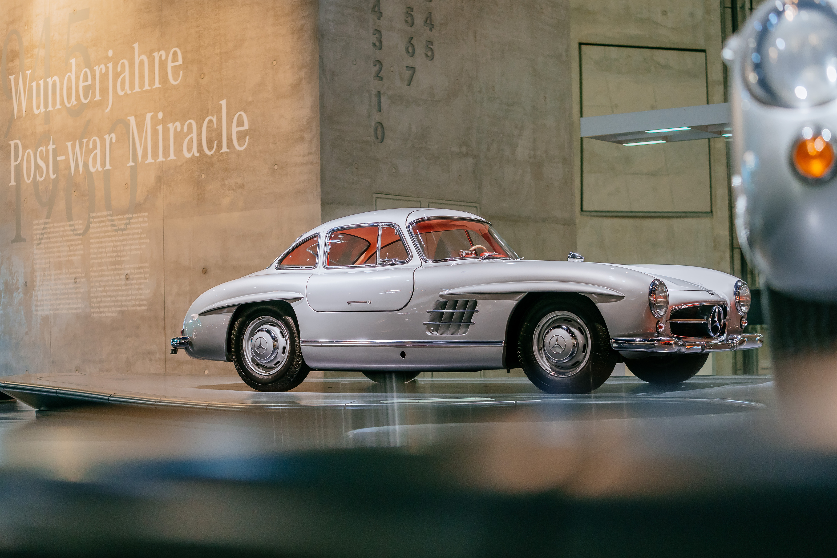 Silberner Mercedes-Benz 300 SL Coupé mit Flügeltüren in der Seitenansicht, ausgestellt im Mercedes-Benz-Museum.