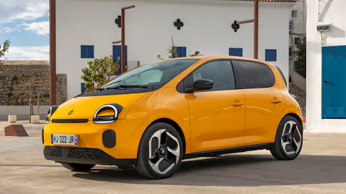Ein orangegelber Renault Twingo E-Tech steht auf einer gepflasterten Fläche.