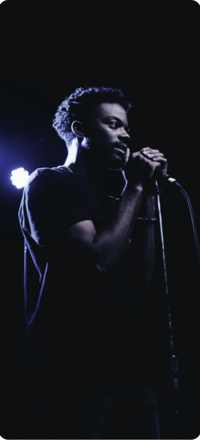 Man looking intently into the crowd as he sings into the mic