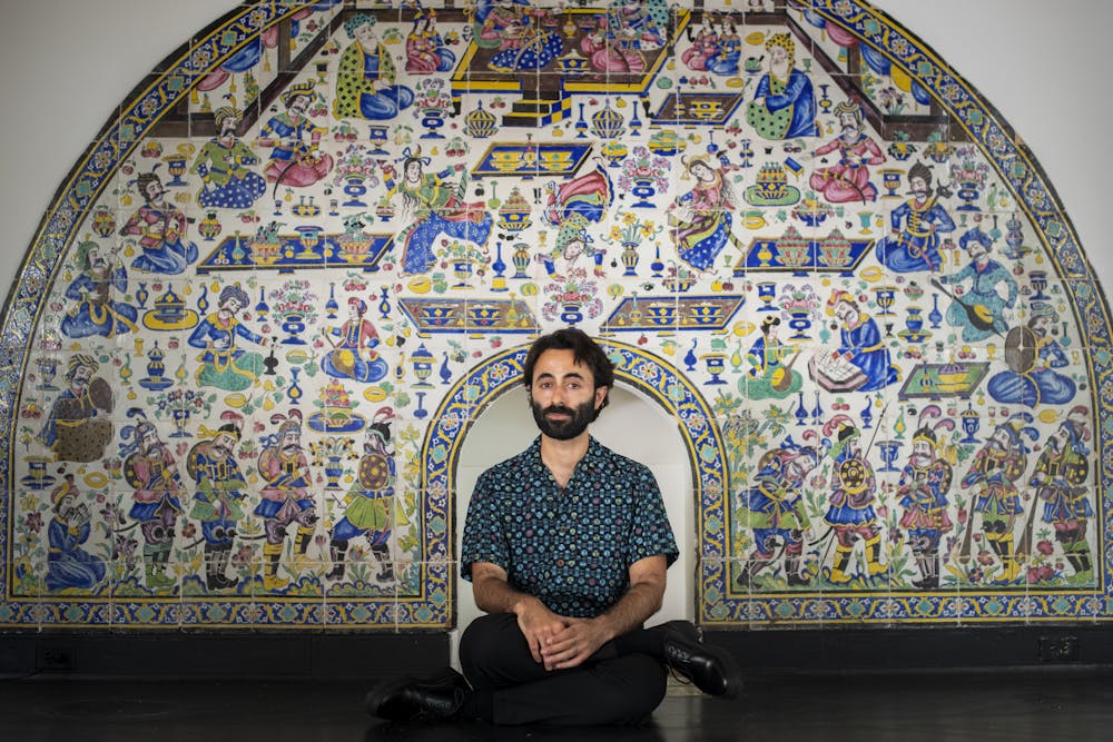 Artist, Navid Sinaki, sits in front of the Shangri La Qajar fireplace looking forward. 