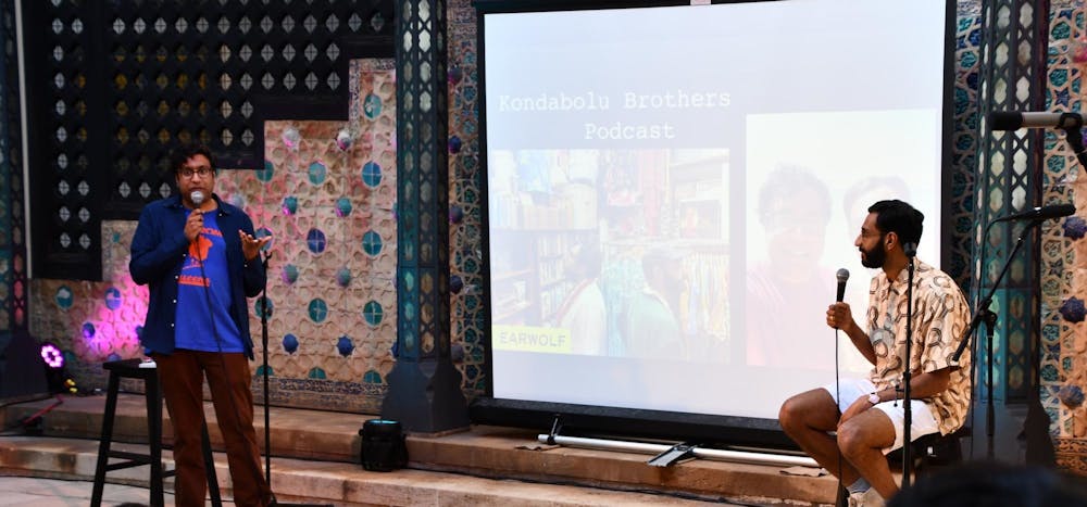Hari and Ashok Kondabolu talking in front of a group of people in the Central Courtyard at Shangri La. 