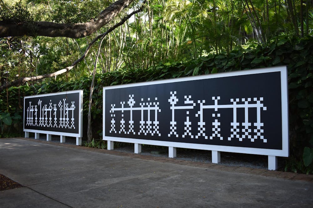 Two large mural panels that feature a black background with pixelated white block letters - by artist Bahia Shehab. 
