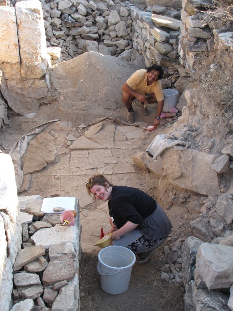 Quinn Ferris and Volkan Sevinç cleaning an inscription on the shattered marble floor of the Civil Basilica for photography. (Photo: Kent Severson.)