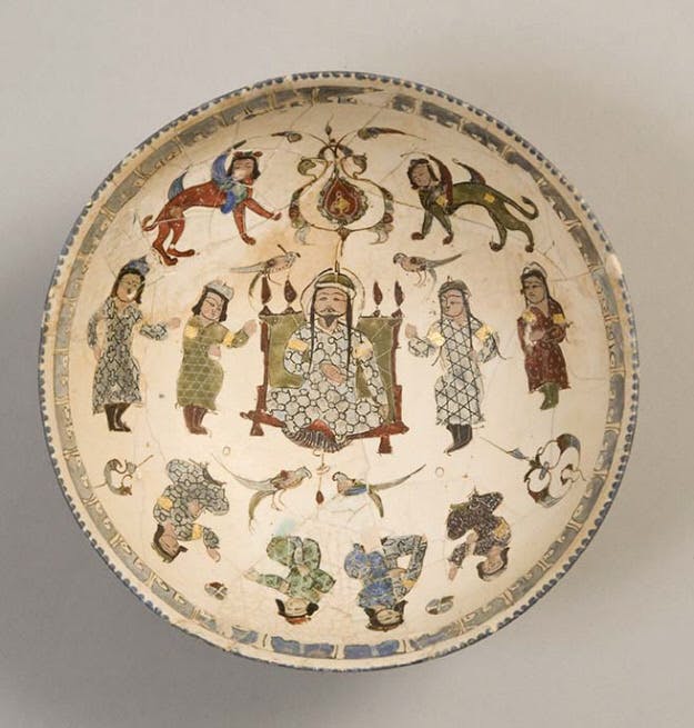 A mina'i bowl of hemispherical form and curving walls rests on short spreading foot. The white interior has an enthroned prince on a gold throne flanked by various attendants. Additional attendants and birds are depicted below while two confronted harpies and two birds flank an arabesque above. A narrow blue border of stylized kufic inscriptions runs below the rim. The exterior features a band of brown naskh on an otherwise unornamented white ground.