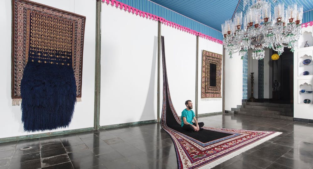 The Textile Gallery (formerly the Dining Room) at Shangri La with three of artist Faig Ahmed's works on display. Ahmed is sitting on one of his large-scale carpet works.