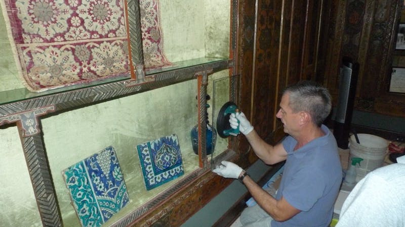 Conservator Kent Severson installs a pane of protective glass in the objects vitrine. Doris Duke Foundation for Islamic Art, Honolulu, Hawai‘i.