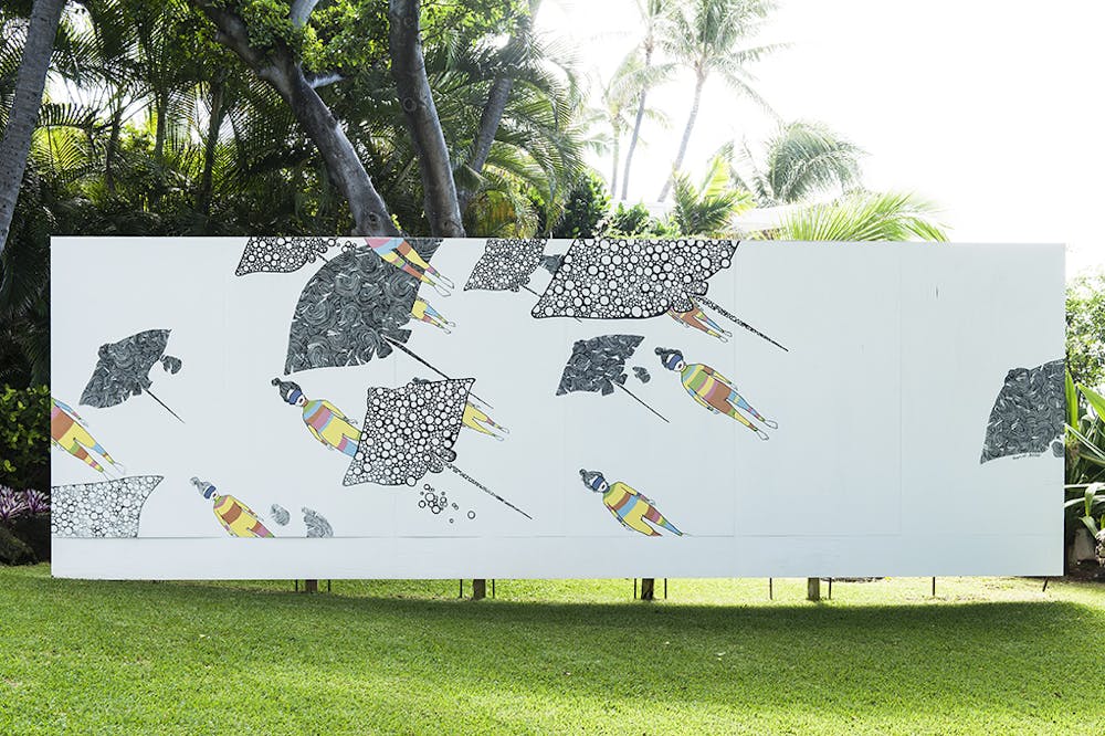 Women with colorful wet suits swim among stingrays on a white rectangular mural background. 