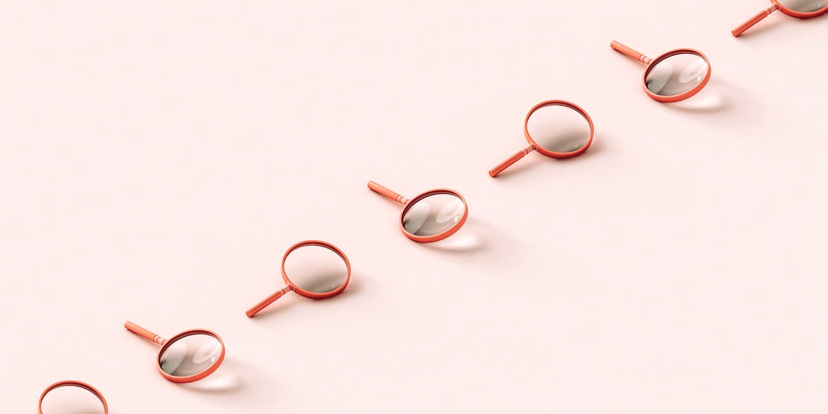 A row of pink 3D magnifying glasses crossing the frame on pale pink background.