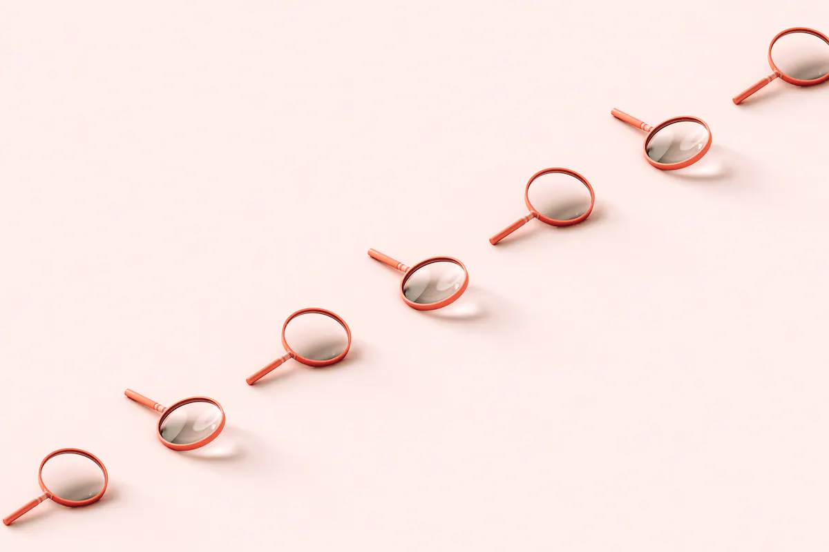 A row of pink 3D magnifying glasses crossing the frame on pale pink background.