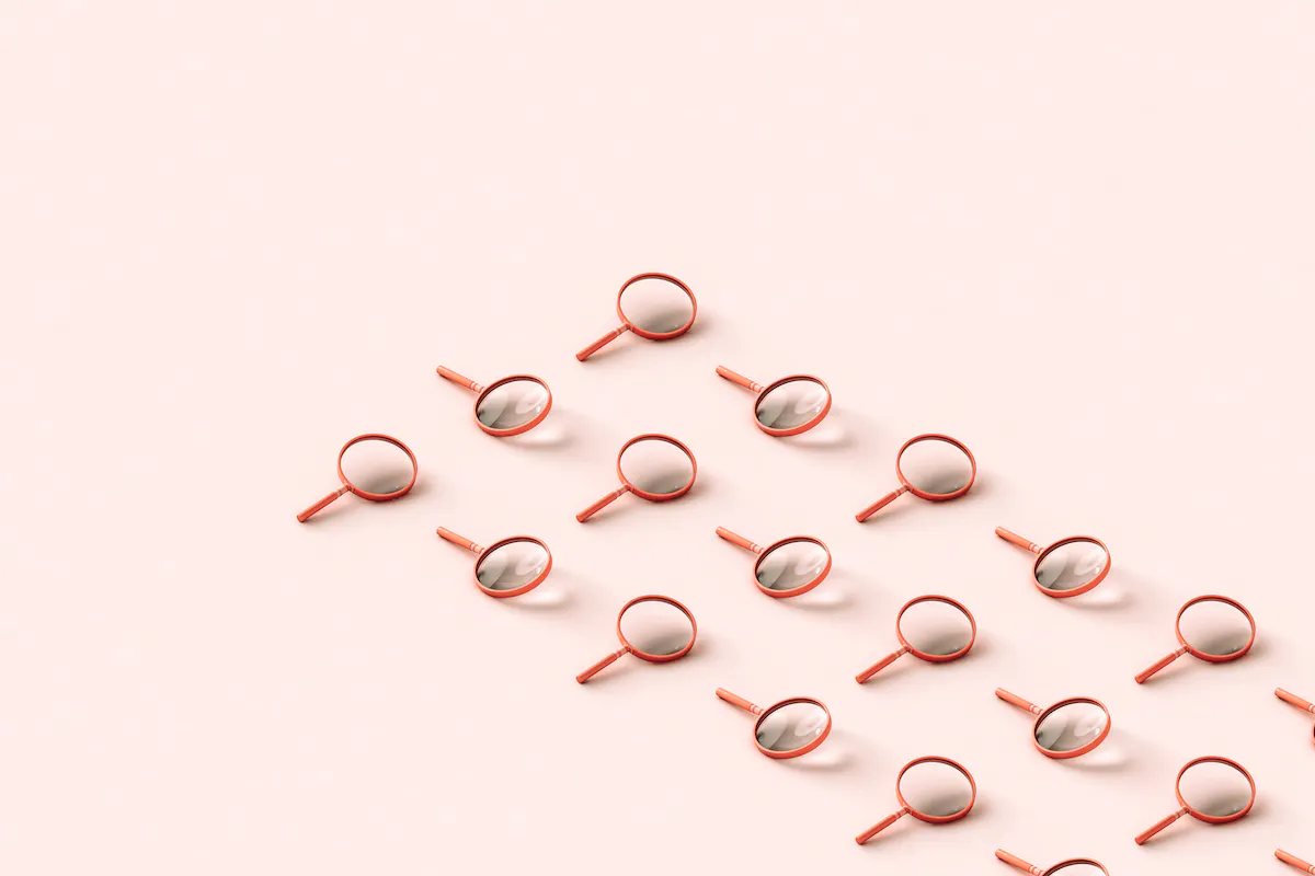 Pink 3D magnifying glasses in a three diagonal rows on pale pink background.