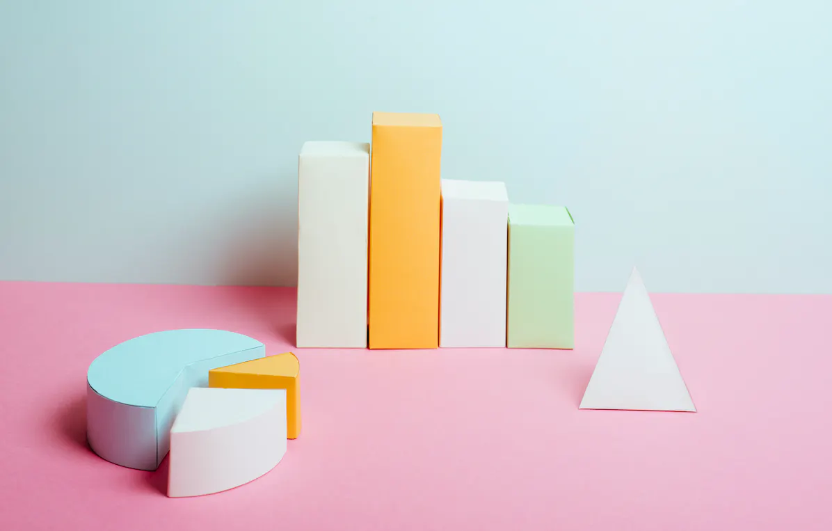 Pastel-colored 3-dimensional blocks arragned in the shapes of a pie chart and column chart.