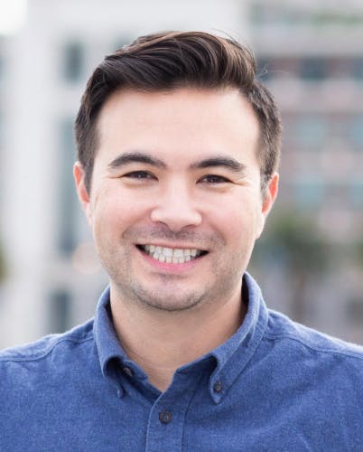 Jeff Sakasegawa is smiling widely. He has short hair, dark brown and he's wearing a blue collared shirt.