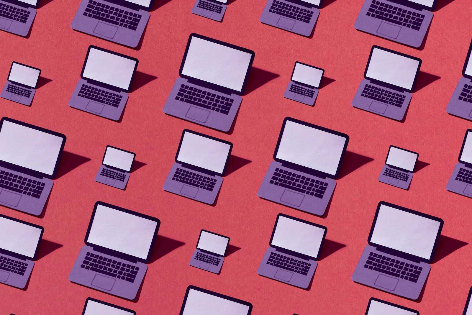Many drawings of an open, purple laptop with a blank screen on a red background. The laptops are in different sizes and cast shadows to left.