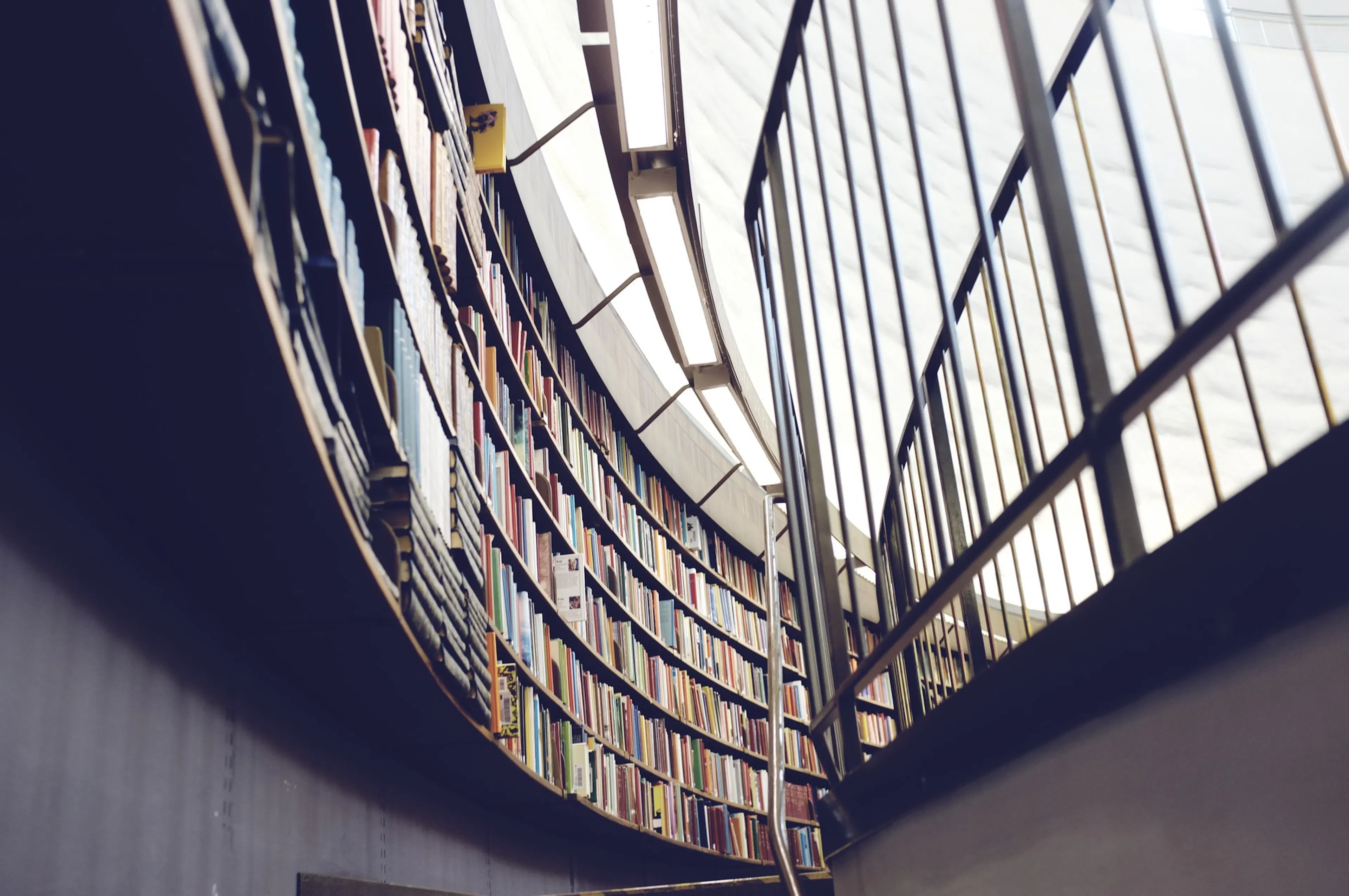 A round library wall filled with books faced by a railing. Photo by Patrik Göthe on Unsplash.