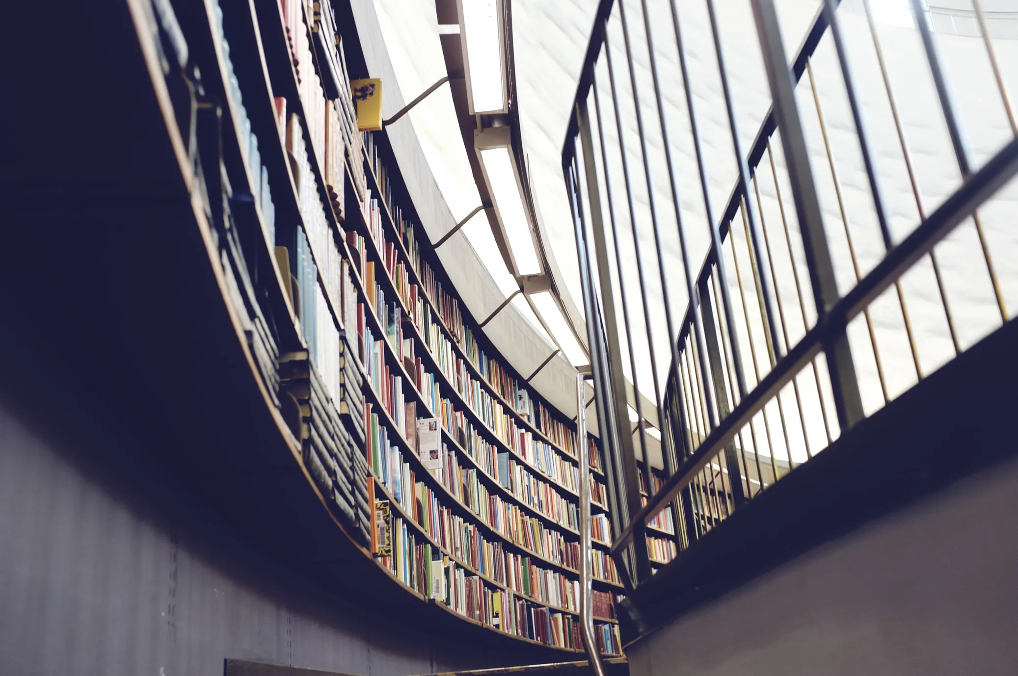 A round library wall filled with books faced by a railing. Photo by Patrik Göthe on Unsplash.