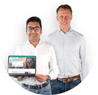 Drive lah founders Gaurav Singhal and Dirk-Jan der Horst. Both founders are smiling and wearing light button-down shirts and jeans. Gaurav is holding a laptop that's open to the Drive lah home page.