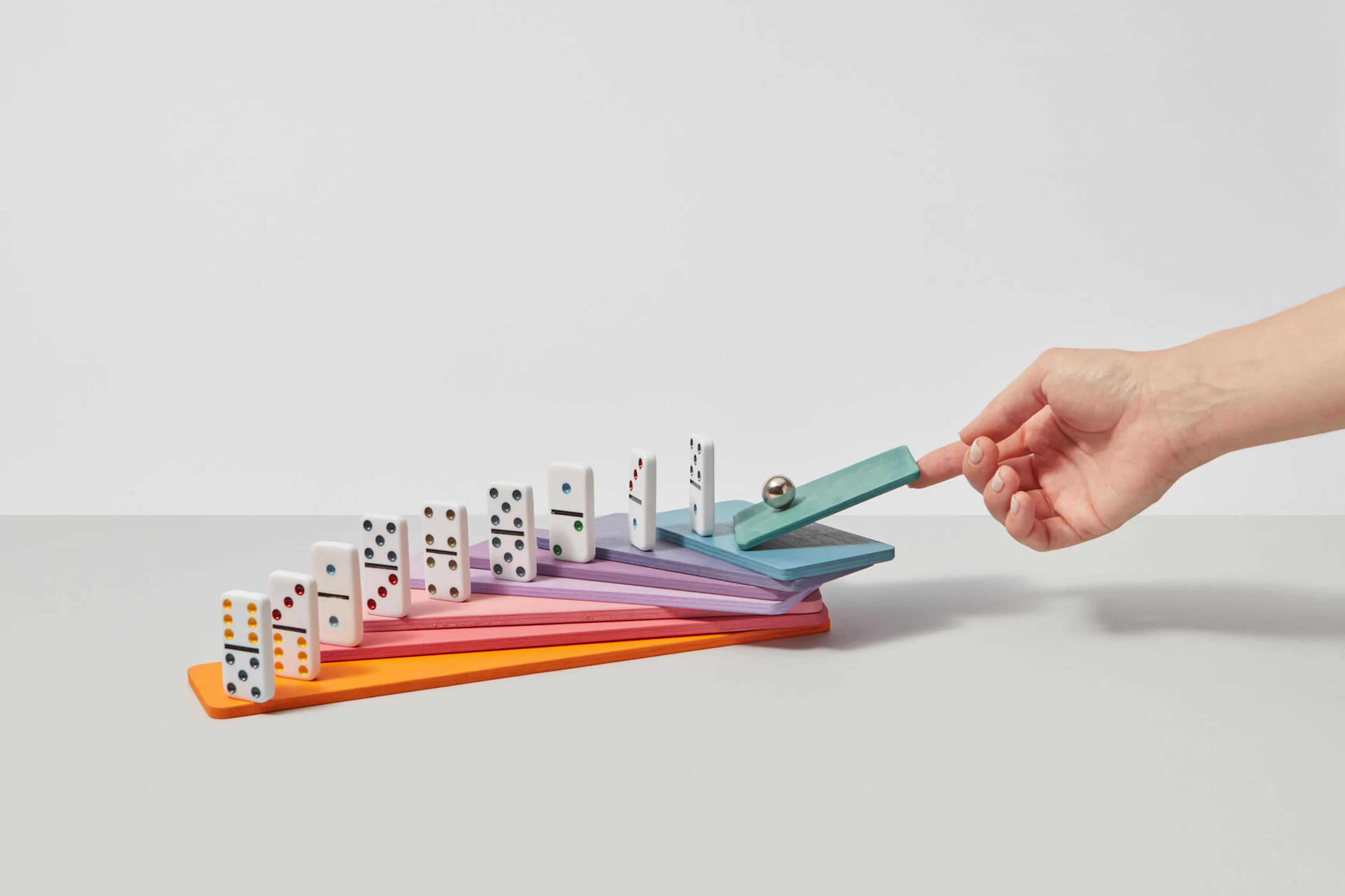 Woman pushing sphere on dominoes.